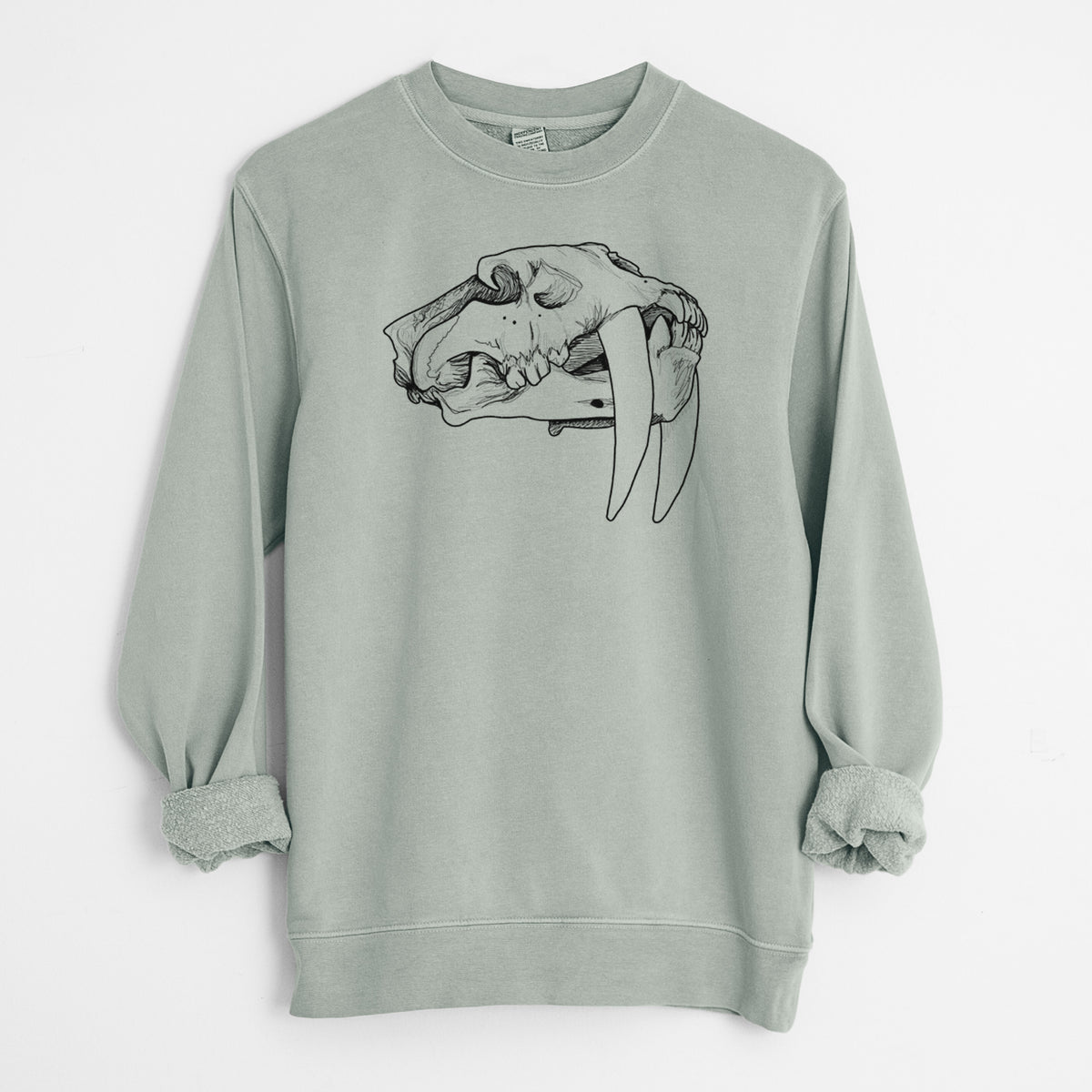 Sage green pigment dyed crewneck sweatshirt laid flat with the sleeves rolled, printed with a detailed black ink illustration of a saber-toothed tiger skull.
