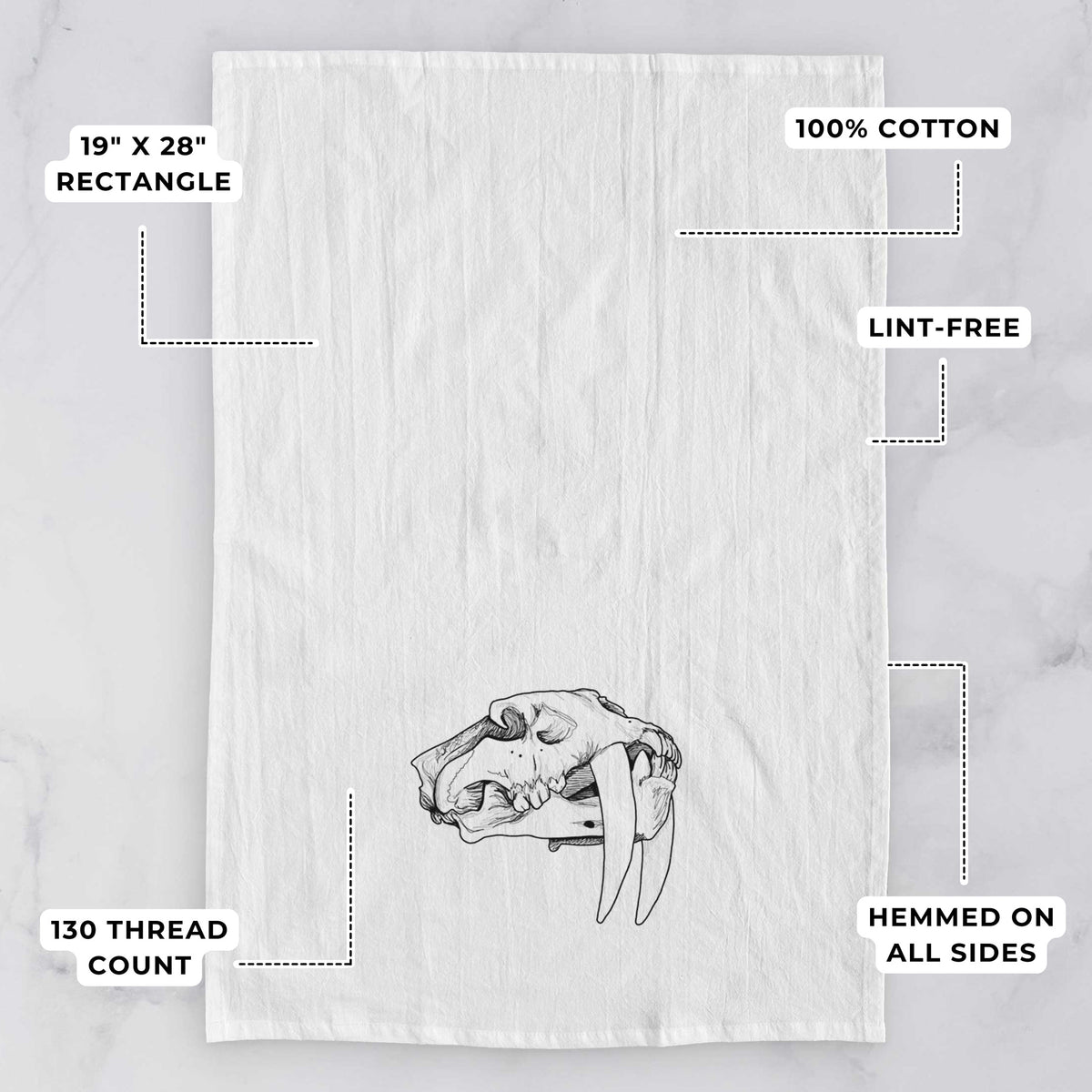White tea towel printed with a detailed black ink illustration of a saber-toothed tiger skull, with feature labels: 19 by 28 inch rectangle, 100% cotton, lint-free, 130 thread count, hemmed on all sides.