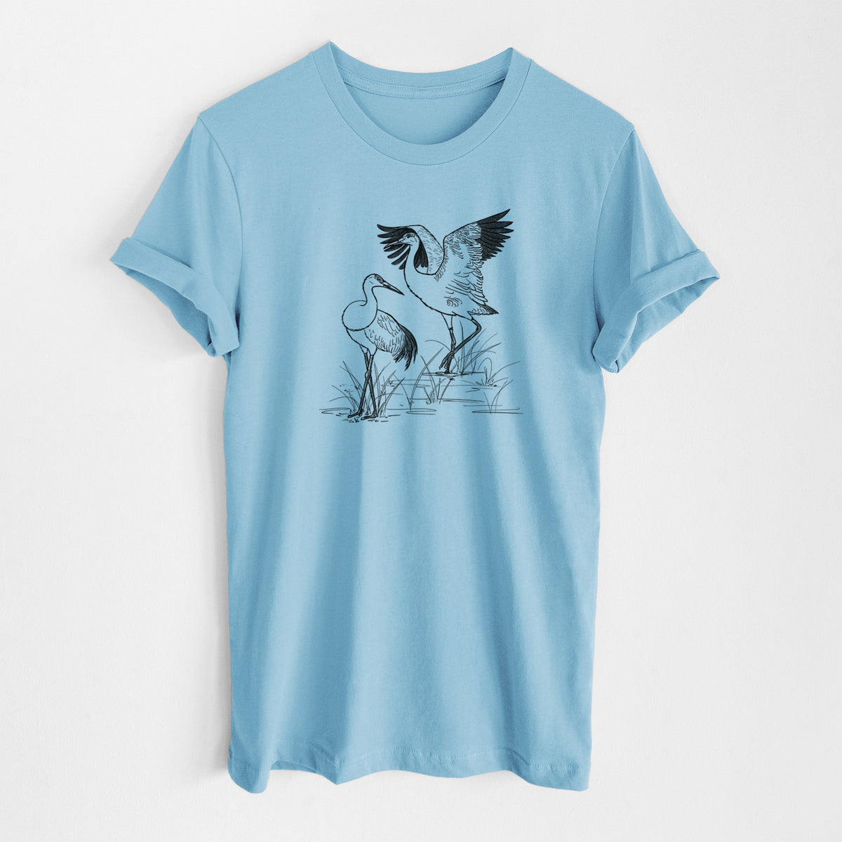 Ocean blue lightweight cotton t-shirt laid flat, printed with a black ink illustration of two sandhill cranes in marsh grass, one with its wings raised.