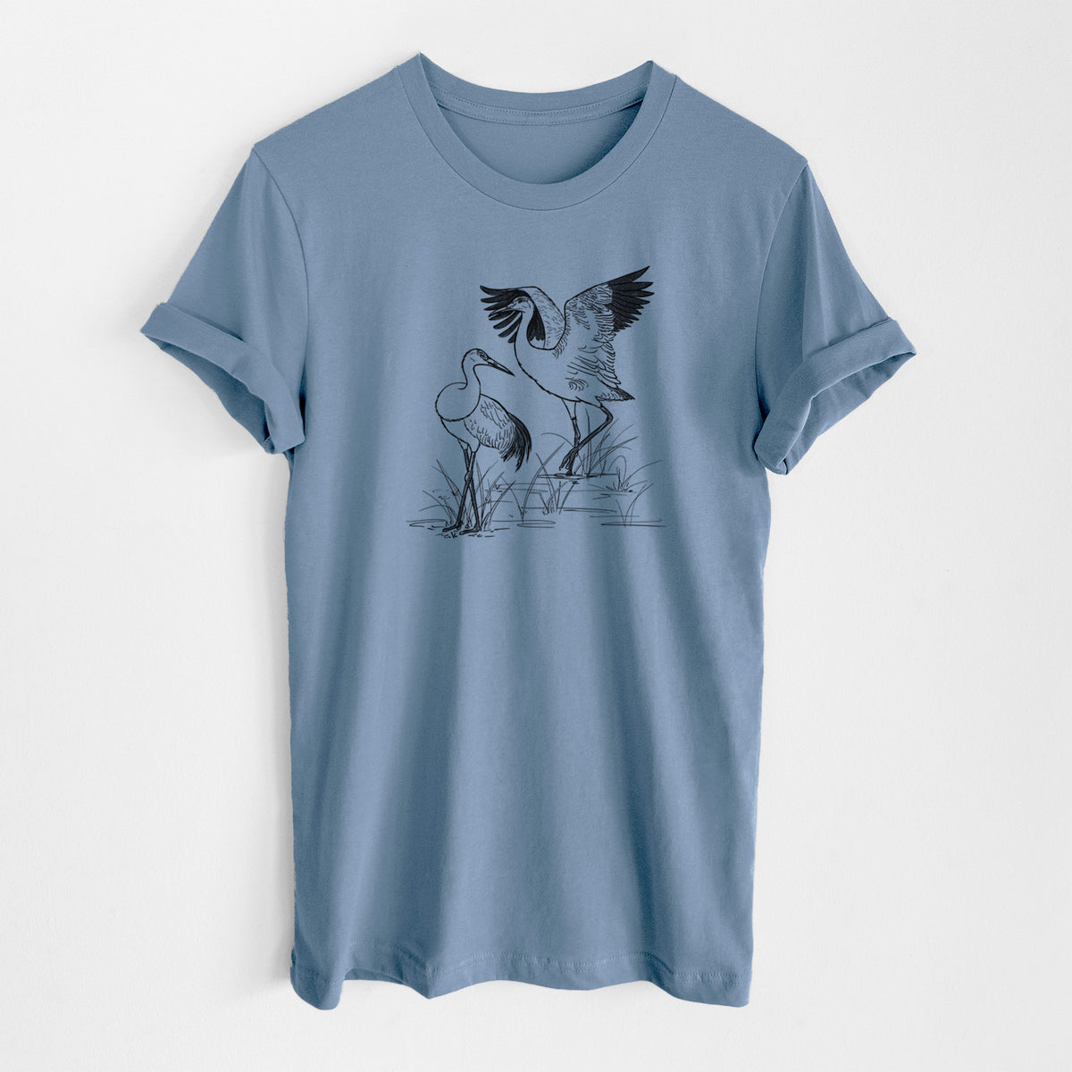Steel blue lightweight cotton t-shirt laid flat, printed with a black ink illustration of two sandhill cranes in marsh grass, one with its wings raised.