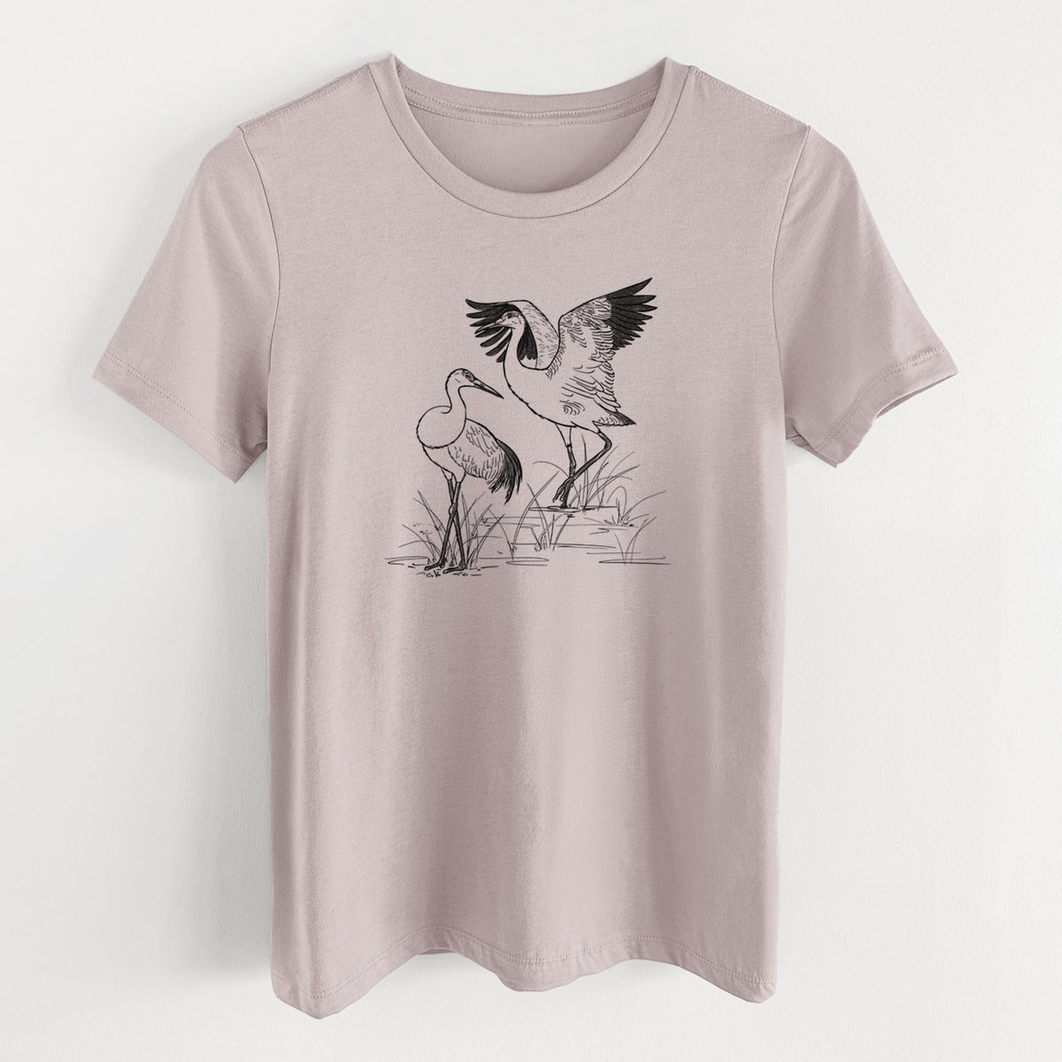 Pink gravel women's relaxed fit cotton t-shirt laid flat, printed with a black ink illustration of two sandhill cranes in marsh grass, one with its wings raised.