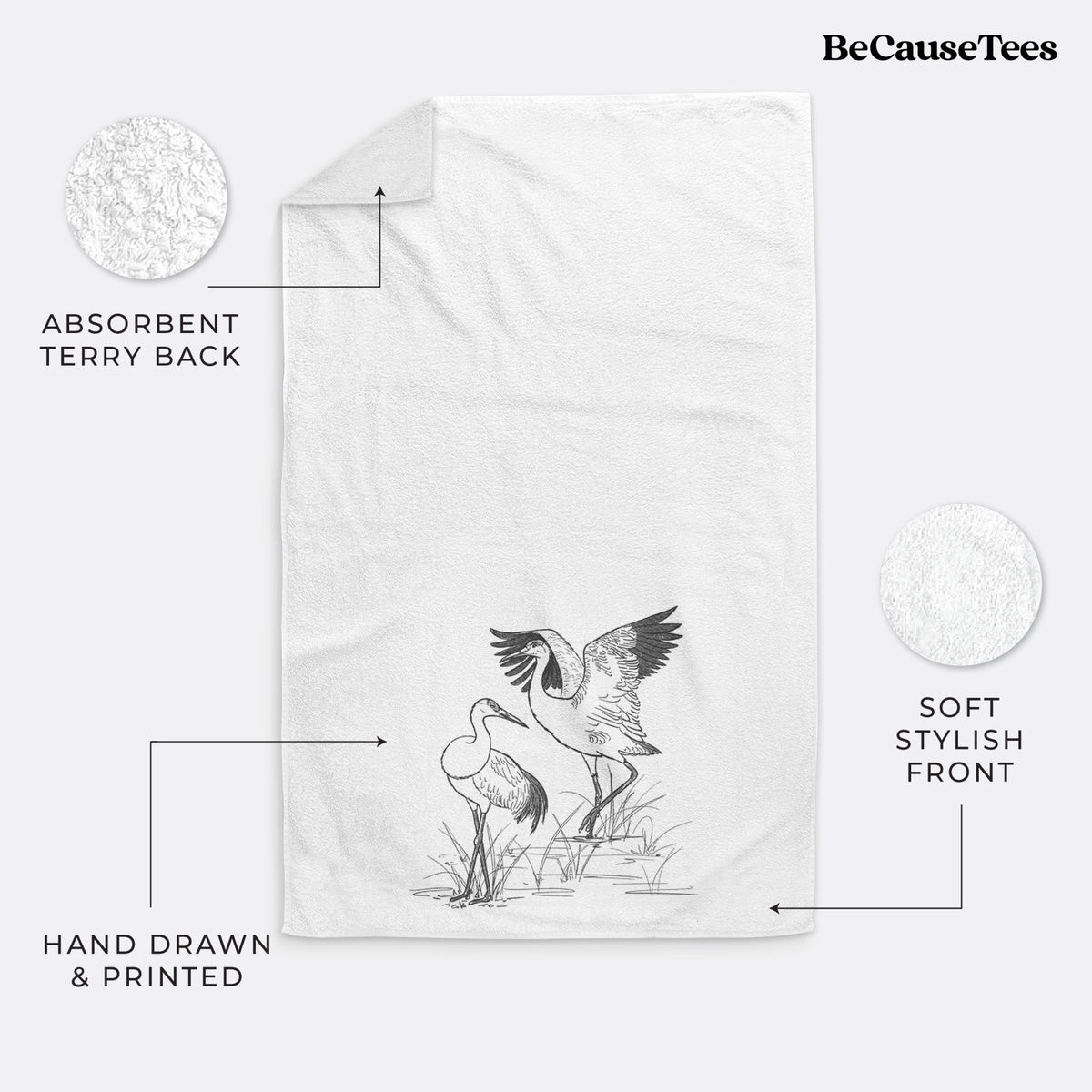 White hand towel printed with a black ink illustration of two sandhill cranes in marsh grass, one with its wings raised.
