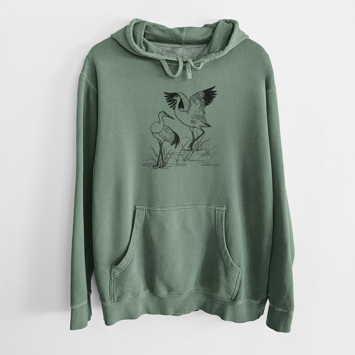 Alpine green pigment dyed hoodie laid flat, printed with a black ink illustration of two sandhill cranes in marsh grass, one with its wings raised.