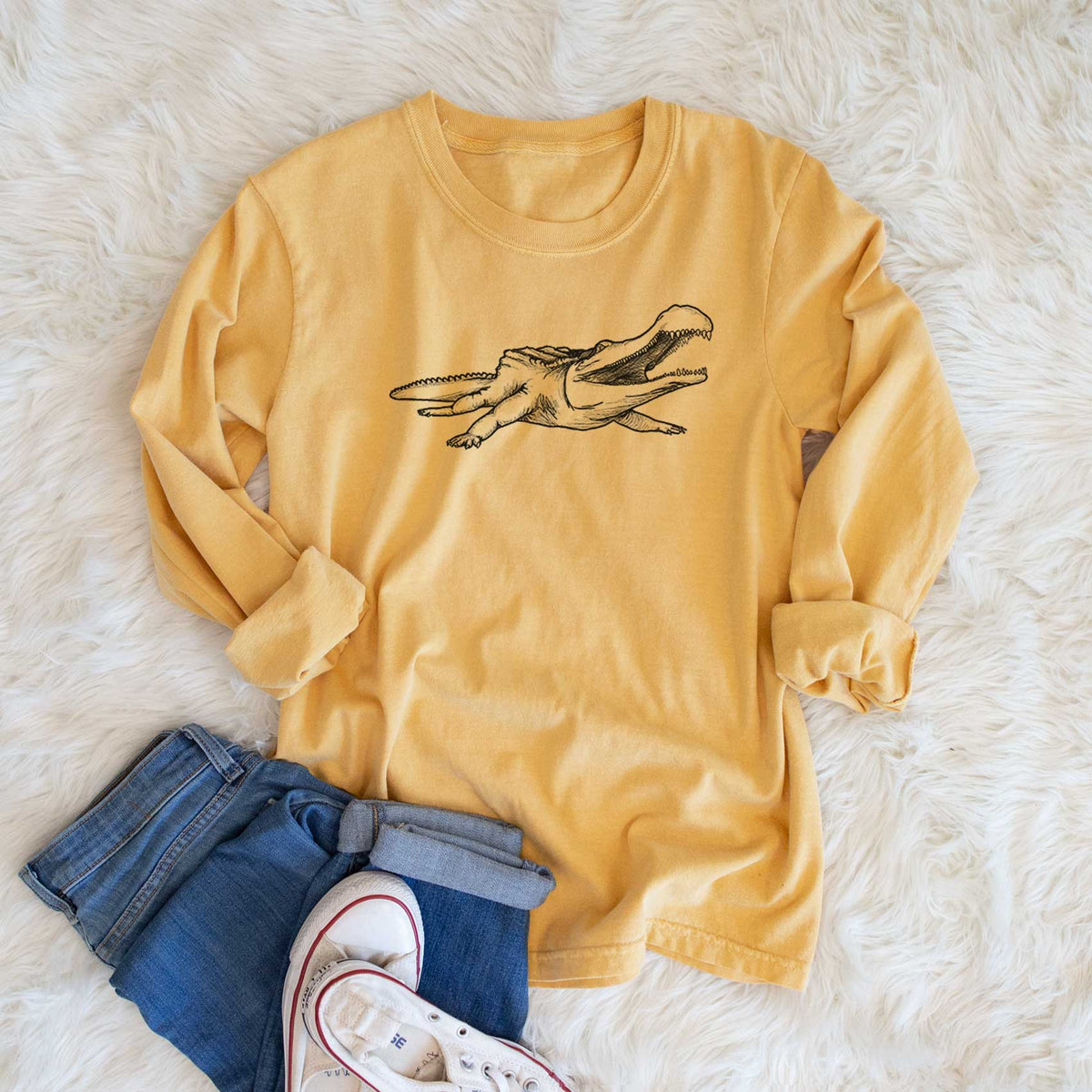 Golden wheat yellow Comfort Colors long sleeve shirt printed with a black ink illustration of a Sarcosuchus, a giant prehistoric crocodile, shown in a lifestyle photo.