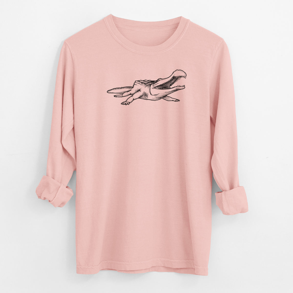 Peachy Comfort Colors long sleeve shirt laid flat with the cuffs rolled, printed with a black ink illustration of a Sarcosuchus, a giant prehistoric crocodile.