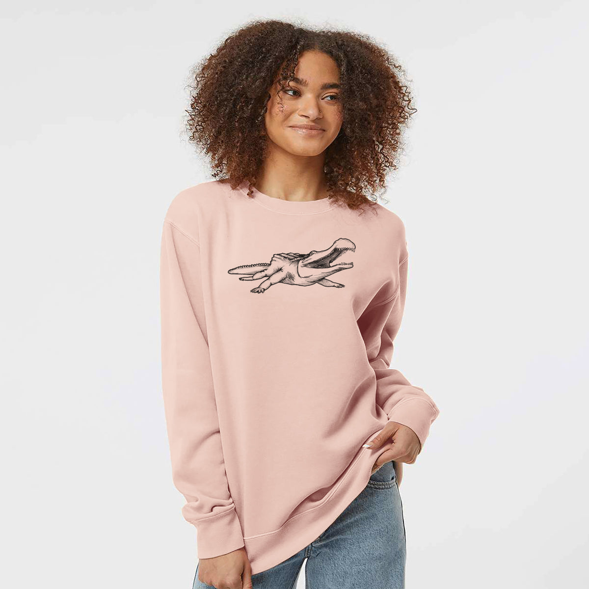Model wearing a dusty pink pigment dyed crewneck sweatshirt printed with a black ink illustration of a Sarcosuchus, a giant prehistoric crocodile.