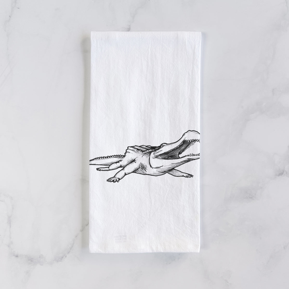 White cotton tea towel laid flat on marble, printed with a black ink illustration of a Sarcosuchus, a giant prehistoric crocodile.