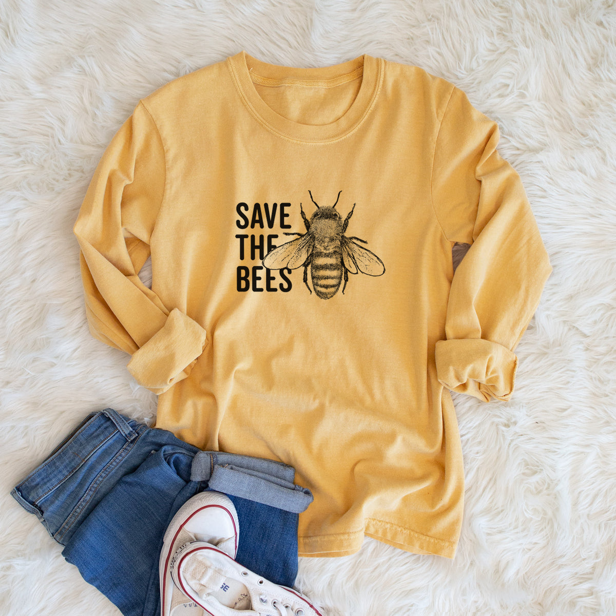 Golden wheat yellow Comfort Colors long sleeve shirt printed with bold black words reading Save the Bees beside a detailed honey bee illustration, shown in a lifestyle photo.