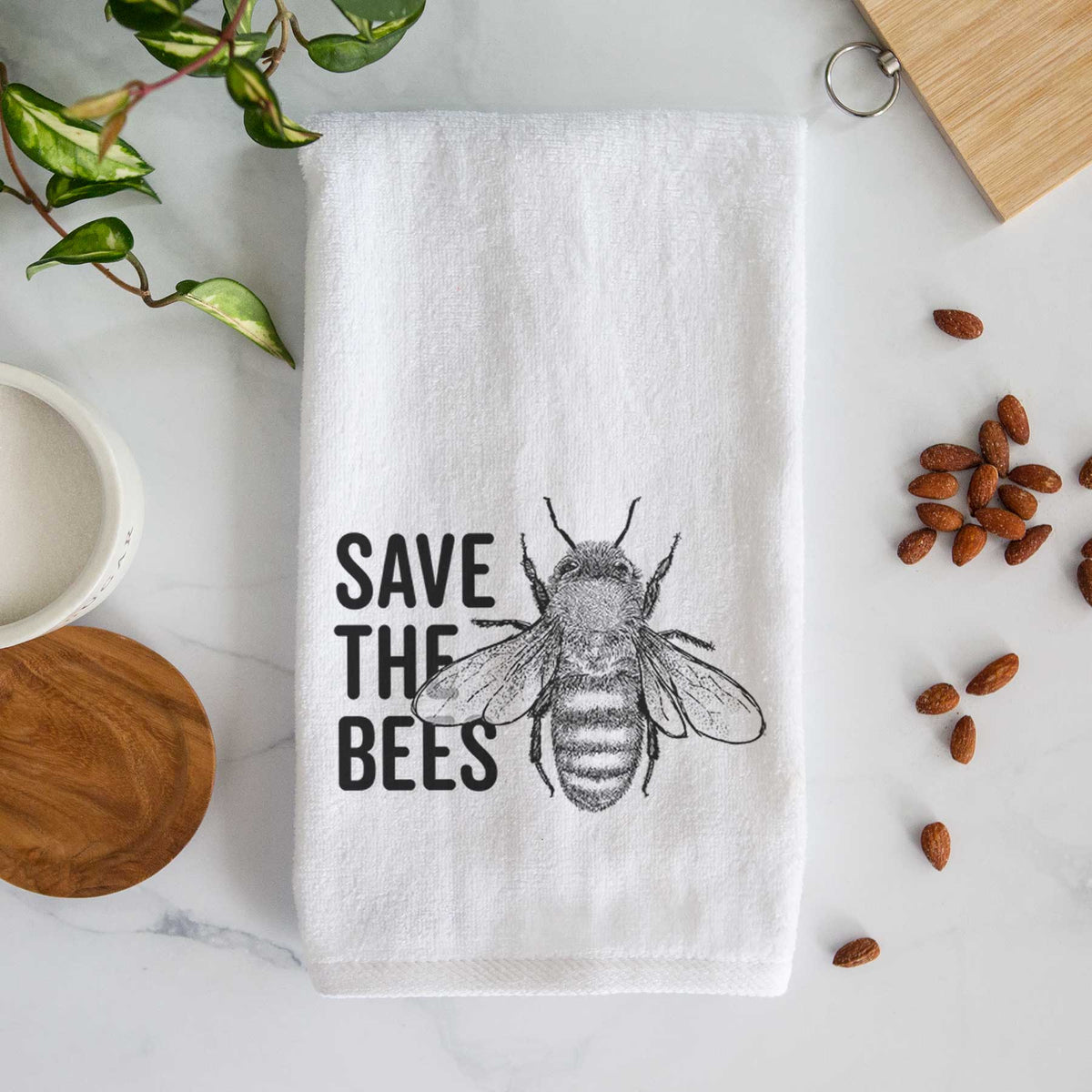 White hand towel printed with bold black words reading Save the Bees beside a detailed honey bee illustration.