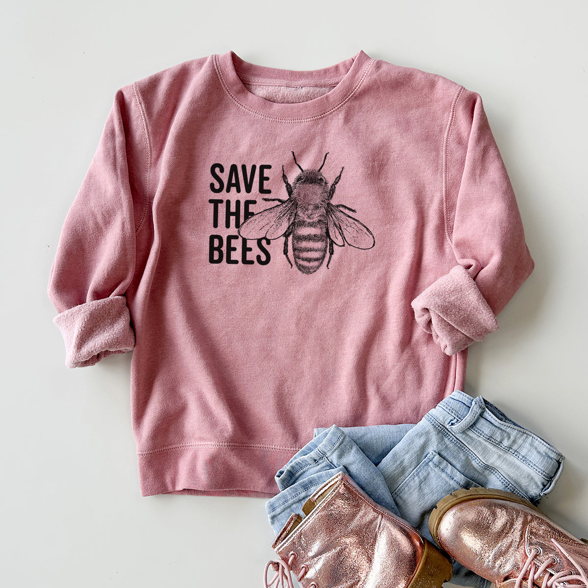 Youth crewneck sweatshirt printed with bold black words reading Save the Bees beside a detailed honey bee illustration, styled flat with jeans and boots.