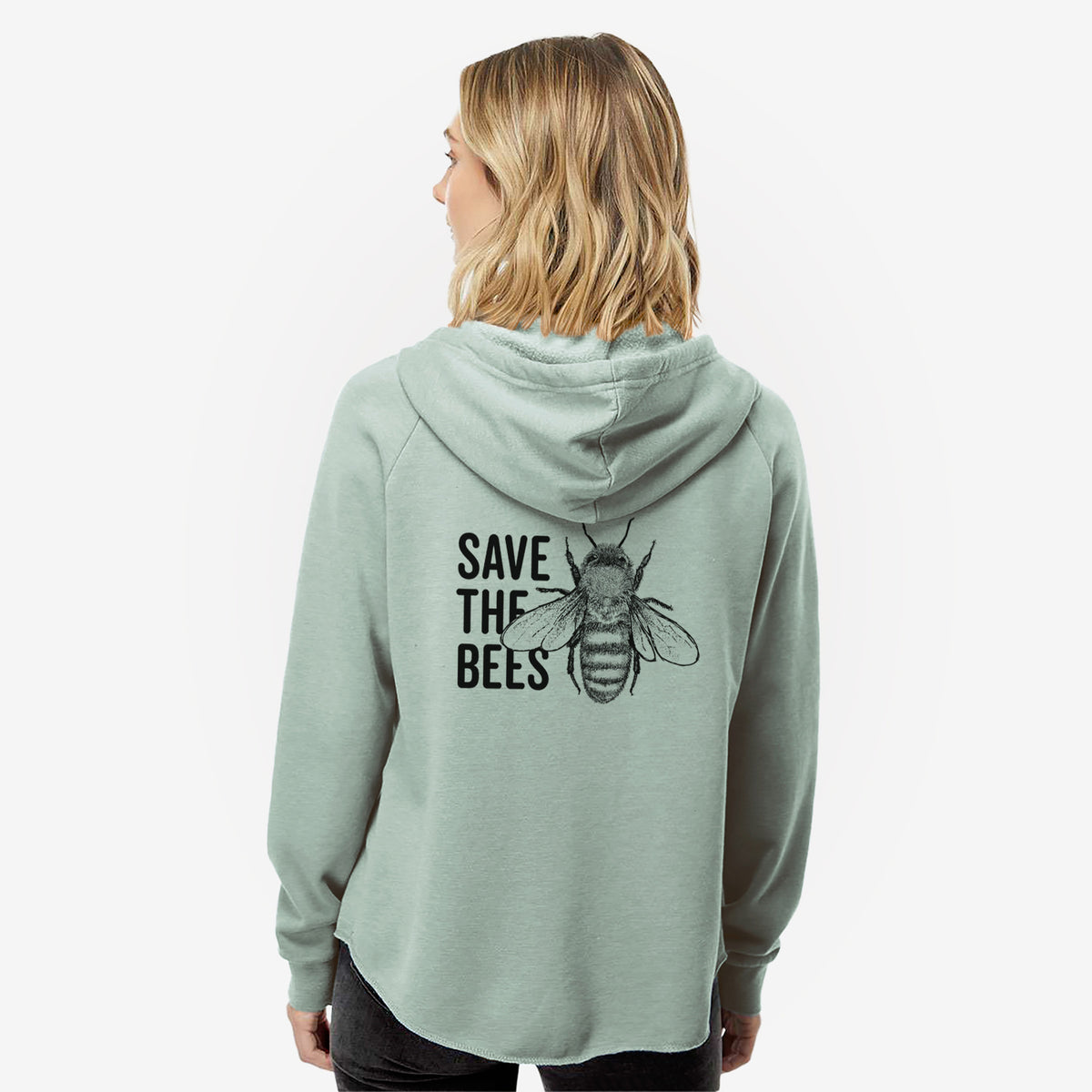 Woman wearing a sage green women's Cali Wave zip-up sweatshirt printed with bold black words reading Save the Bees beside a detailed honey bee illustration, seen from behind.