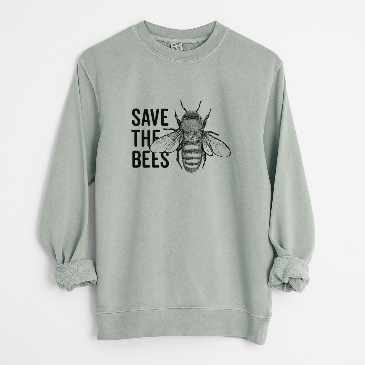 Sage green pigment dyed crewneck sweatshirt laid flat with the sleeves rolled, printed with bold black words reading Save the Bees beside a detailed honey bee illustration.