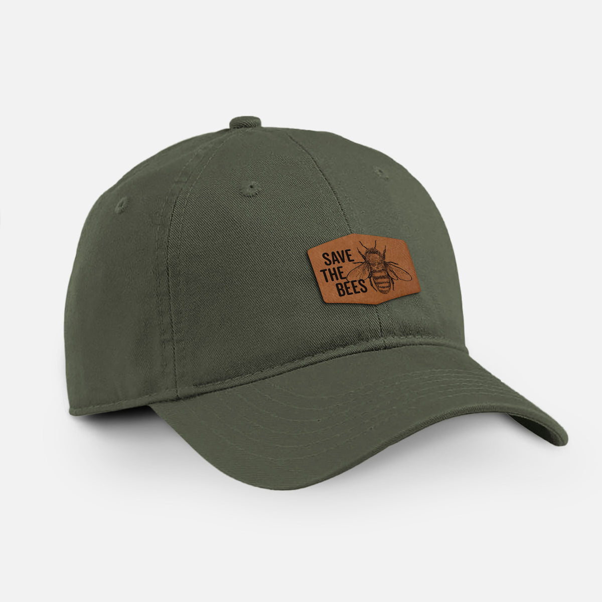 Olive cotton baseball hat with a brown leather patch engraved with the words Save the Bees and a bee on the front.