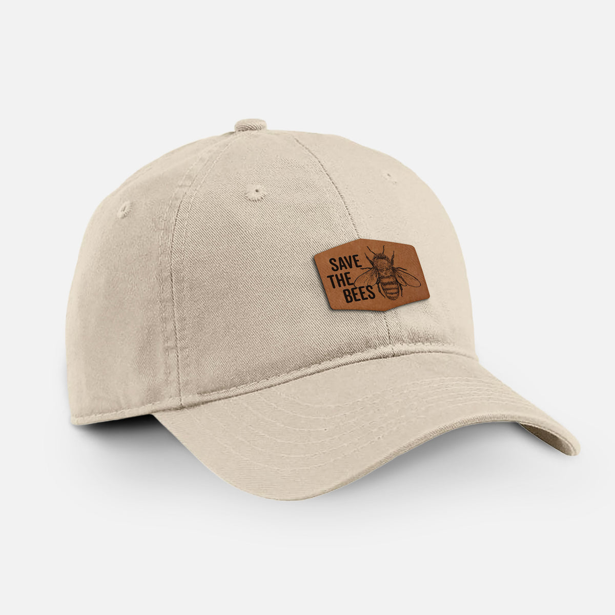 Stone cotton baseball hat with a brown leather patch engraved with the words Save the Bees and a bee on the front.