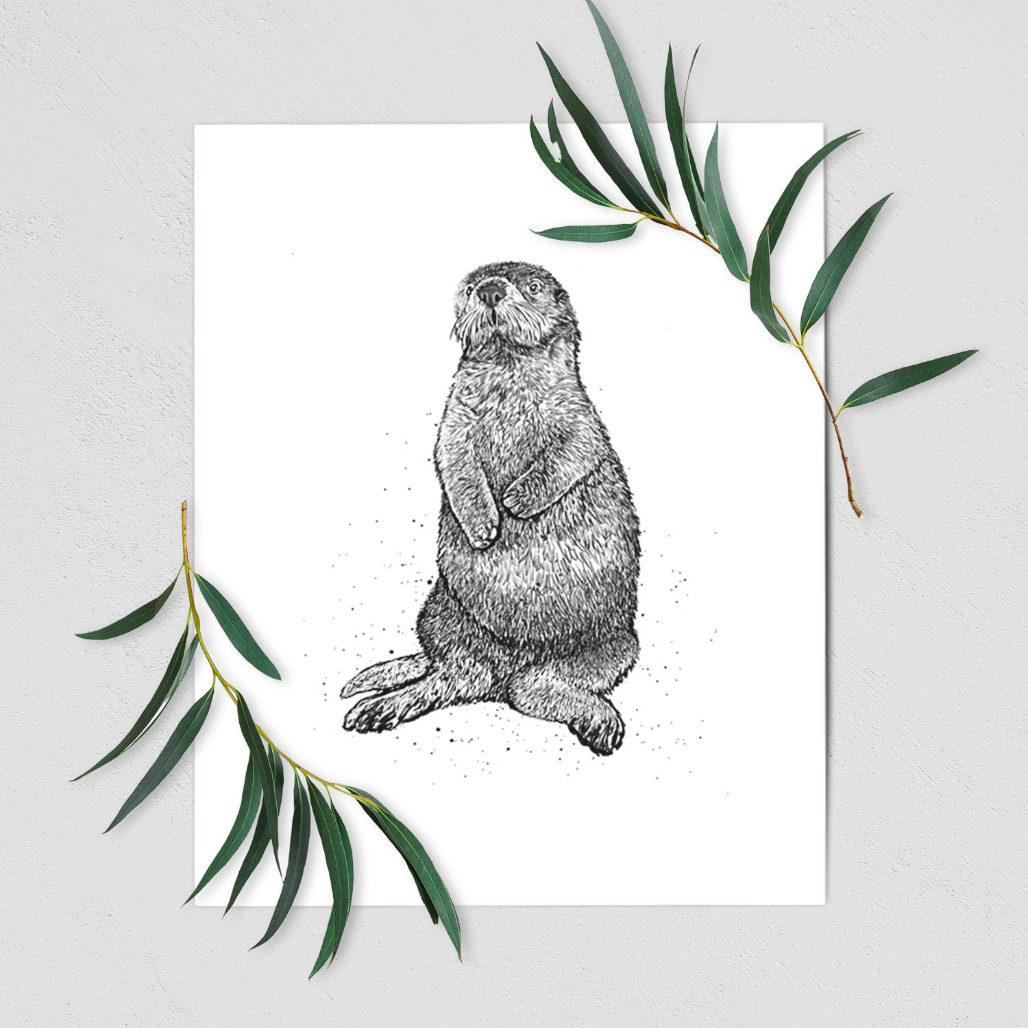 Art print of a detailed black ink illustration of a sea otter sitting upright, shown with eucalyptus leaves.