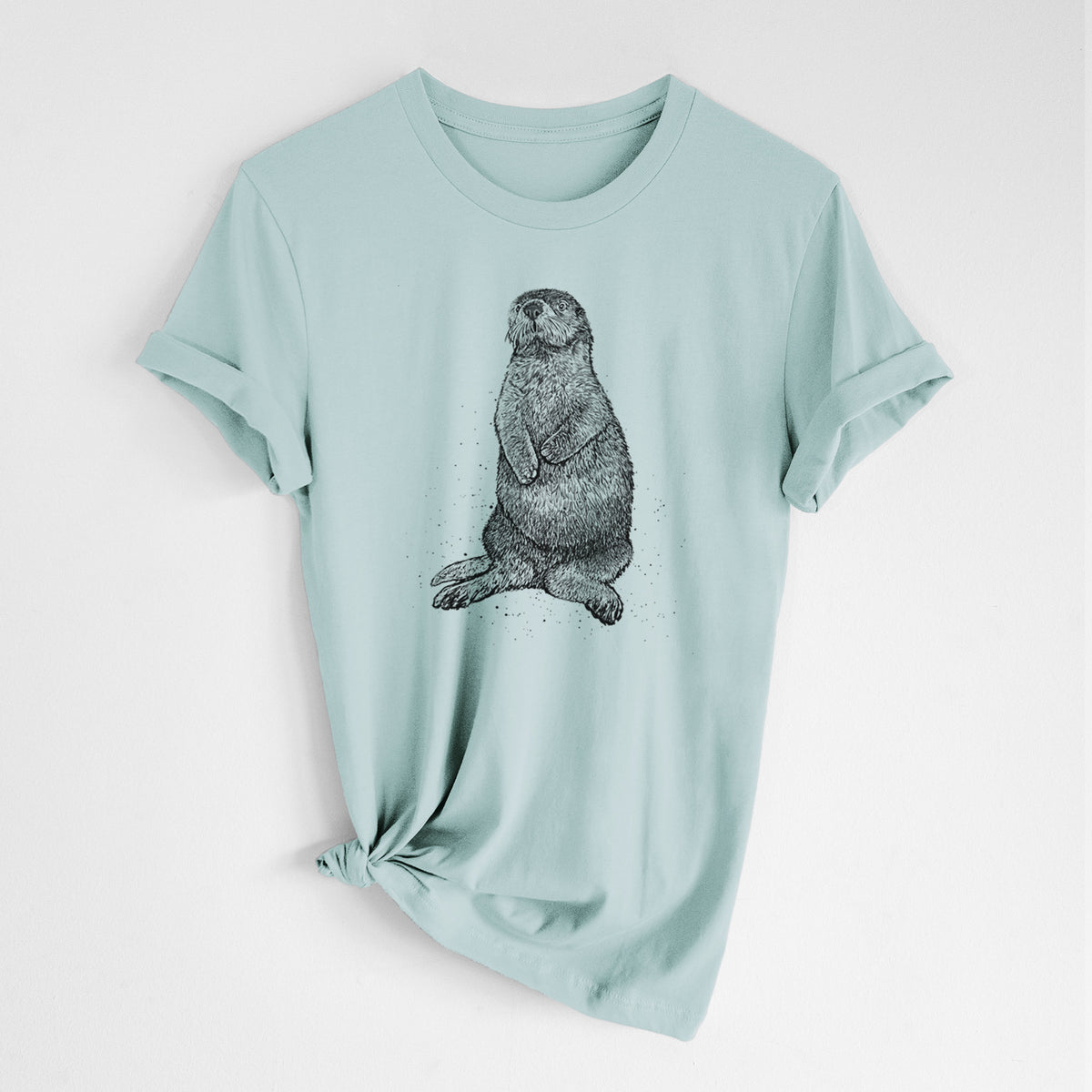 Dusty blue lightweight cotton t-shirt laid flat with the sleeves rolled, printed with a detailed black ink illustration of a sea otter sitting upright.