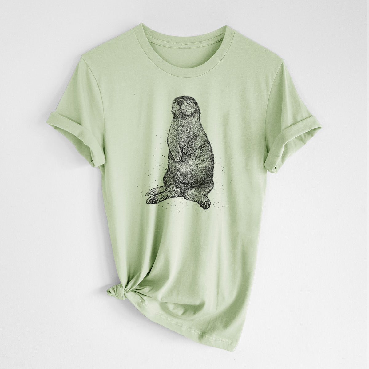 Spring green lightweight cotton t-shirt laid flat with the sleeves rolled, printed with a detailed black ink illustration of a sea otter sitting upright.