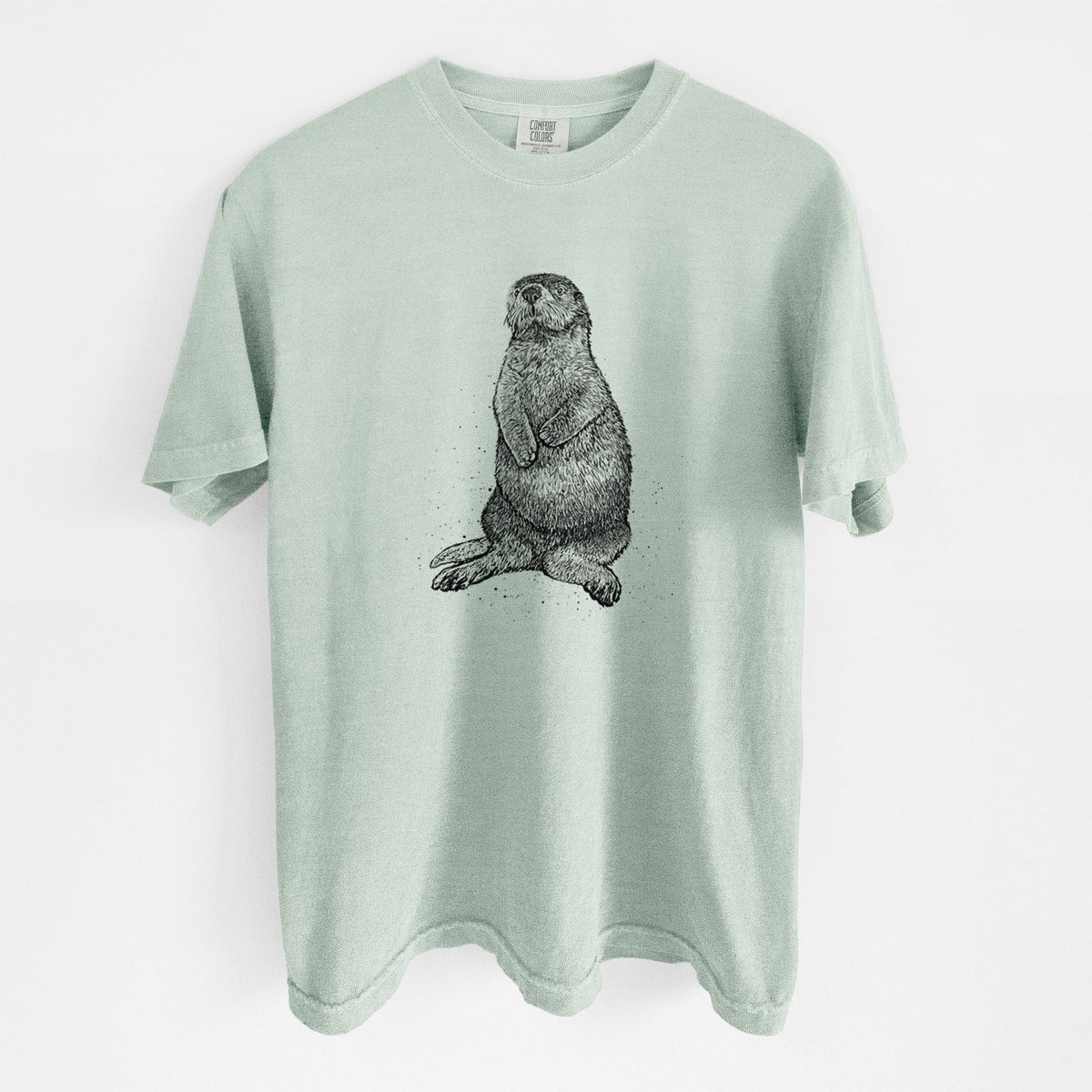 Bay green Comfort Colors t-shirt laid flat, printed with a detailed black ink illustration of a sea otter sitting upright.