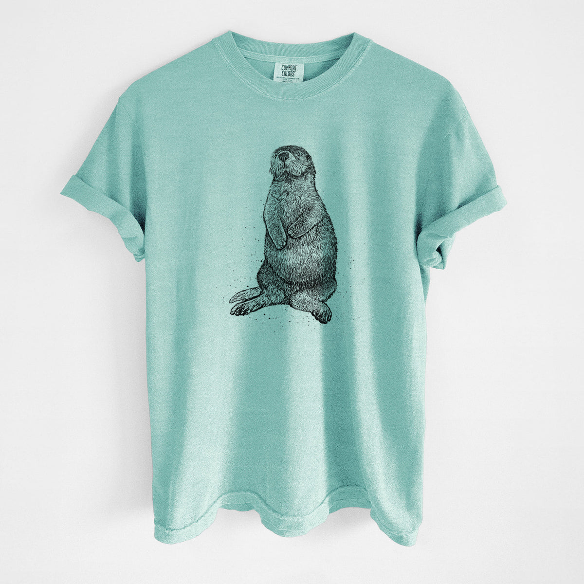 Chalky mint Comfort Colors t-shirt laid flat, printed with a detailed black ink illustration of a sea otter sitting upright.