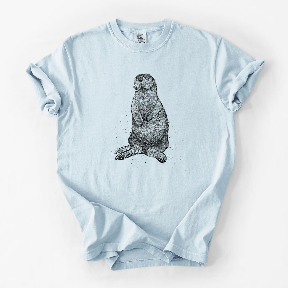 Chambray blue Comfort Colors t-shirt laid flat, printed with a detailed black ink illustration of a sea otter sitting upright.