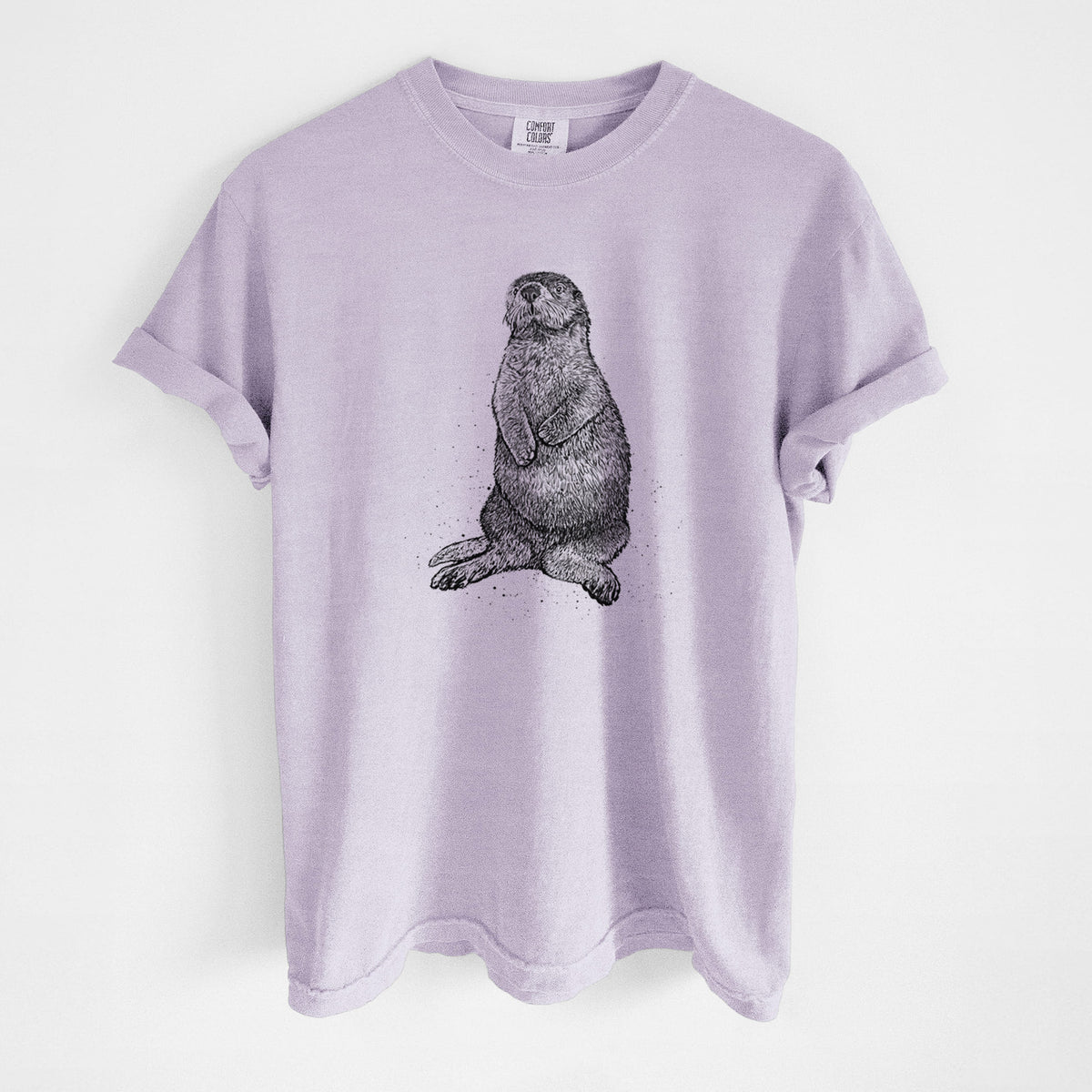Orchid purple Comfort Colors t-shirt laid flat, printed with a detailed black ink illustration of a sea otter sitting upright.