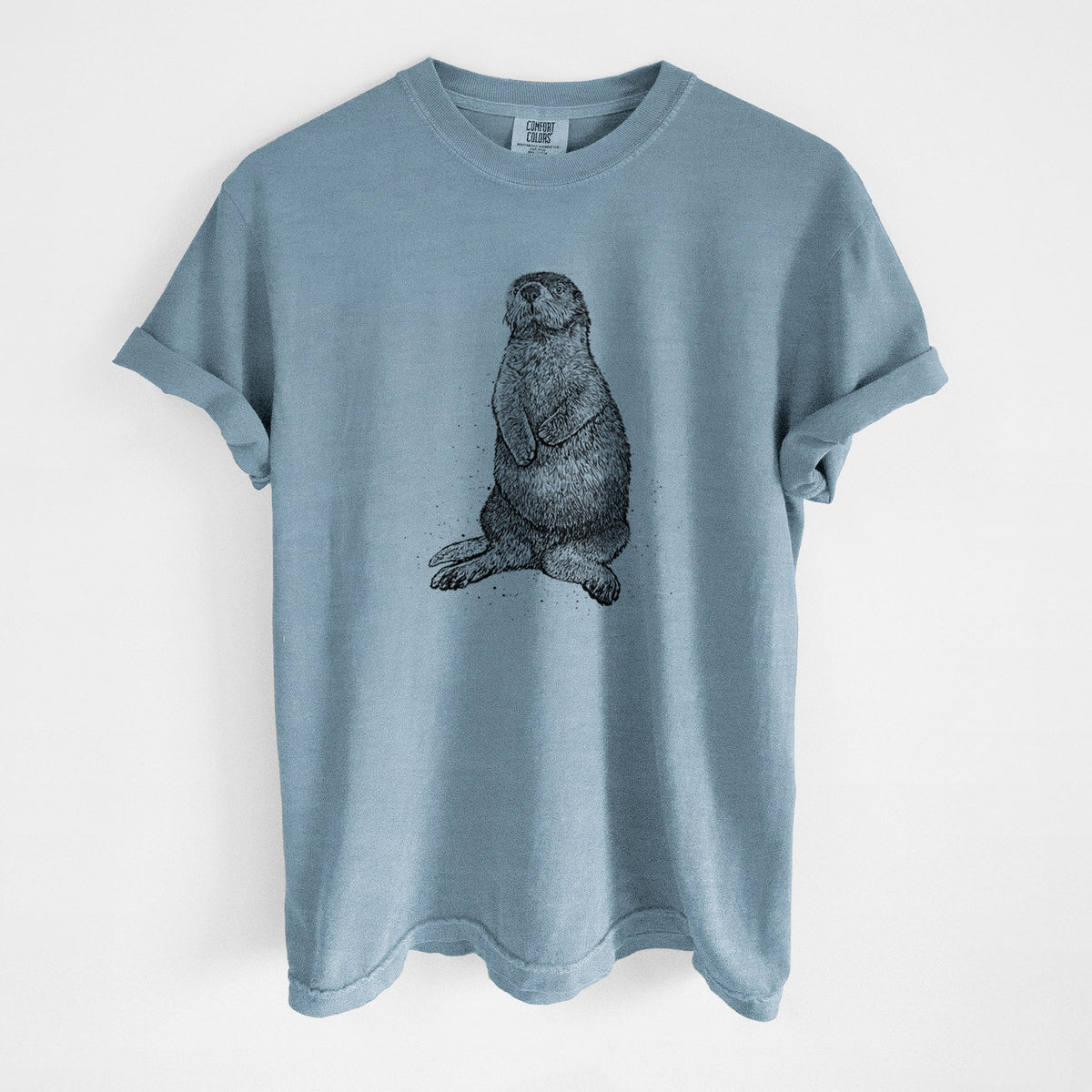 Steel blue Comfort Colors t-shirt laid flat, printed with a detailed black ink illustration of a sea otter sitting upright.