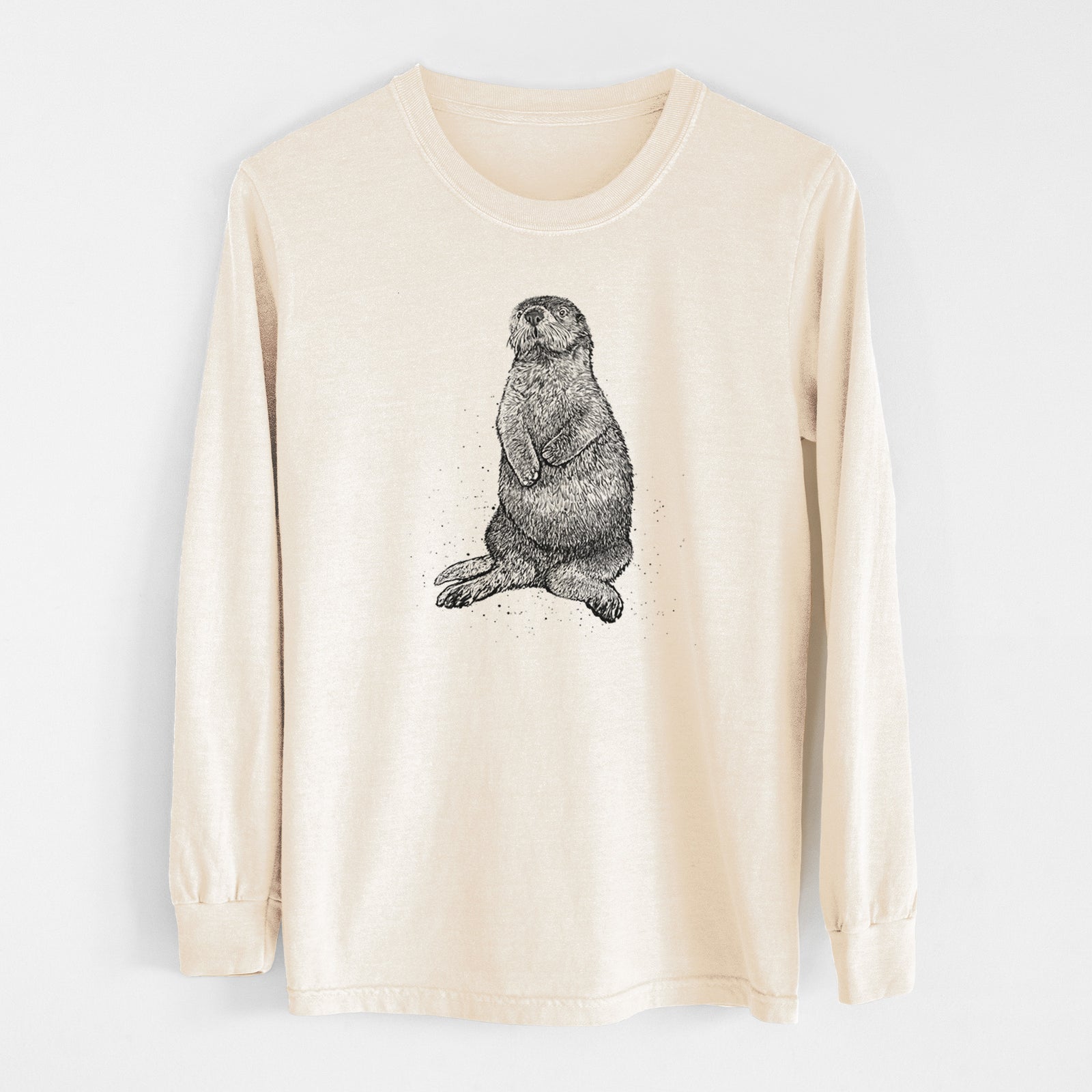 Ivory Comfort Colors long sleeve shirt laid flat, printed with a detailed black ink illustration of a sea otter sitting upright.