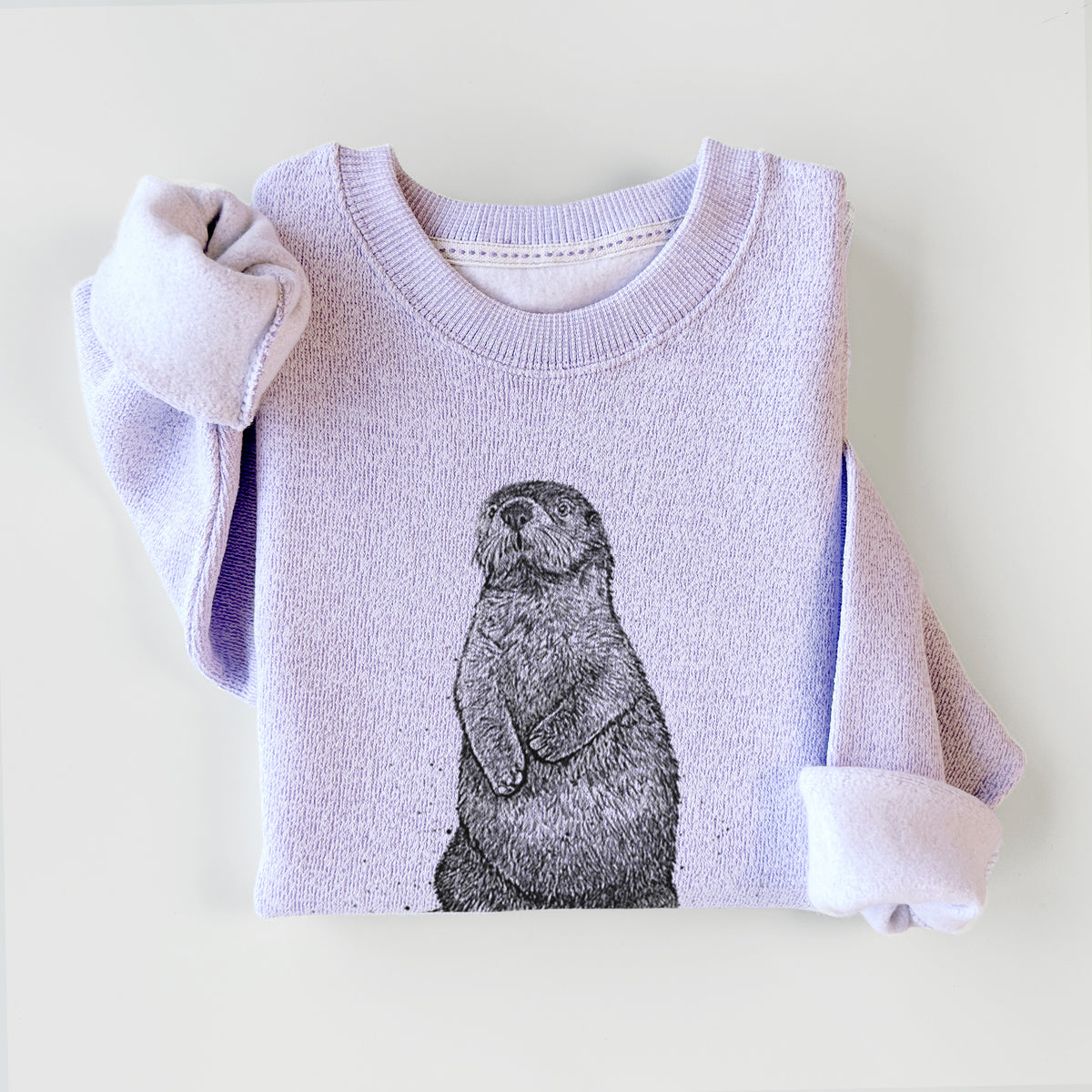 Ice purple knit sweatshirt printed with a detailed black ink illustration of a sea otter sitting upright, styled flat.