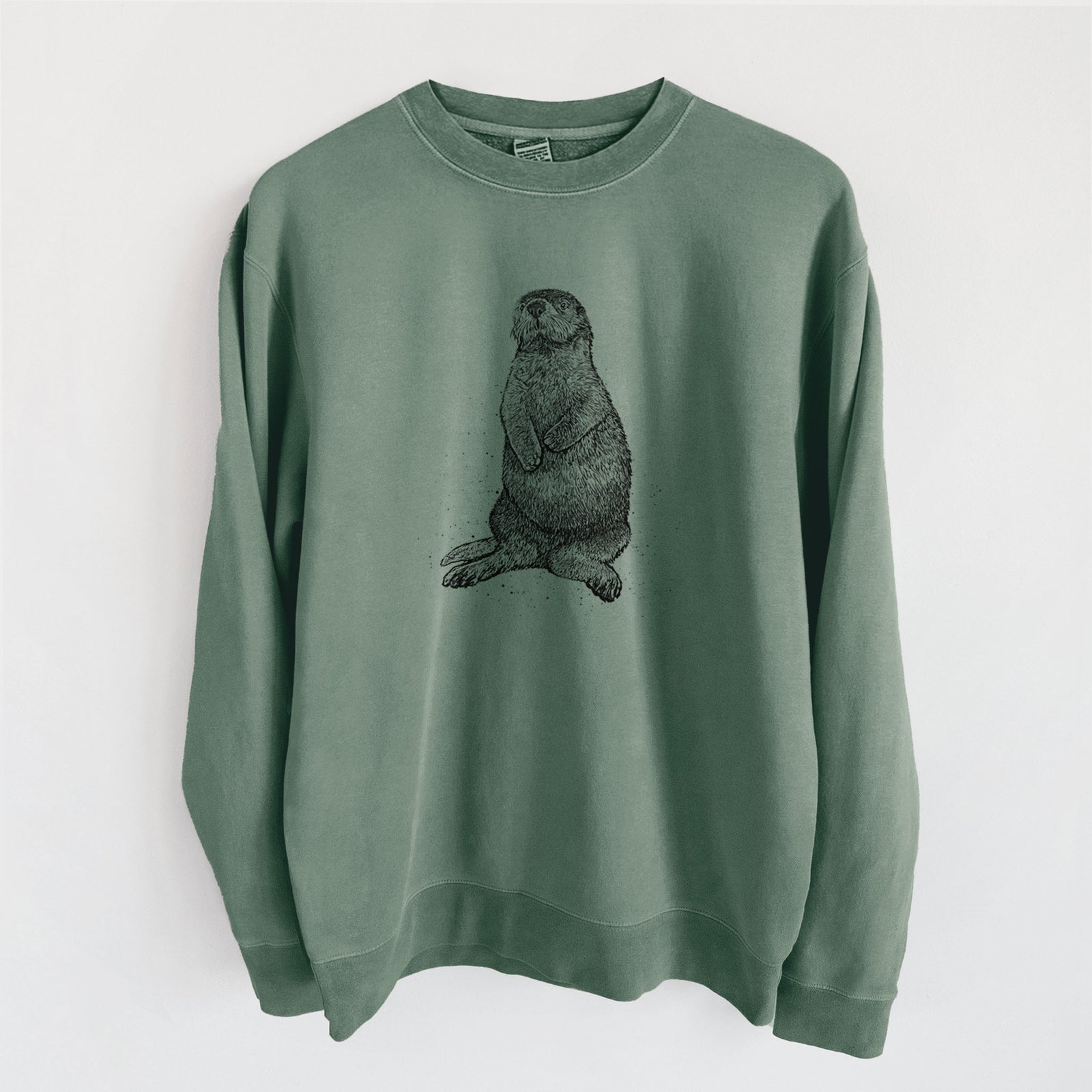 Alpine green pigment dyed crewneck sweatshirt laid flat, printed with a detailed black ink illustration of a sea otter sitting upright.