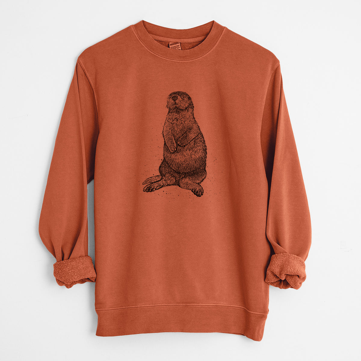Amber orange pigment dyed crewneck sweatshirt laid flat with the sleeves rolled, printed with a detailed black ink illustration of a sea otter sitting upright.