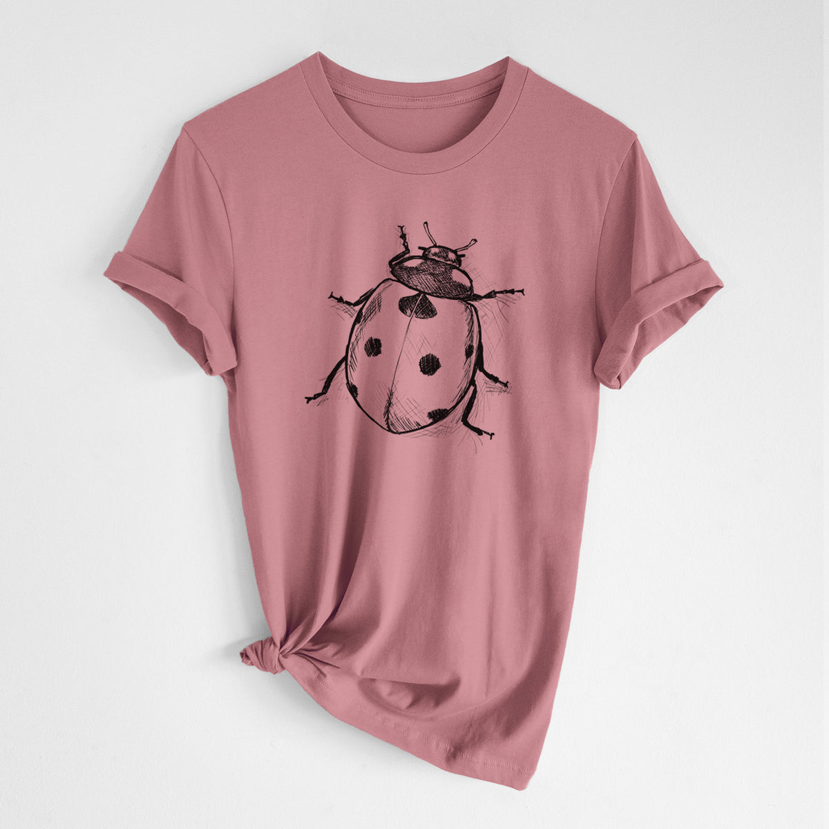 Mauve pink lightweight cotton t-shirt laid flat with the sleeves rolled, printed with a detailed black ink illustration of a seven-spot ladybird beetle.