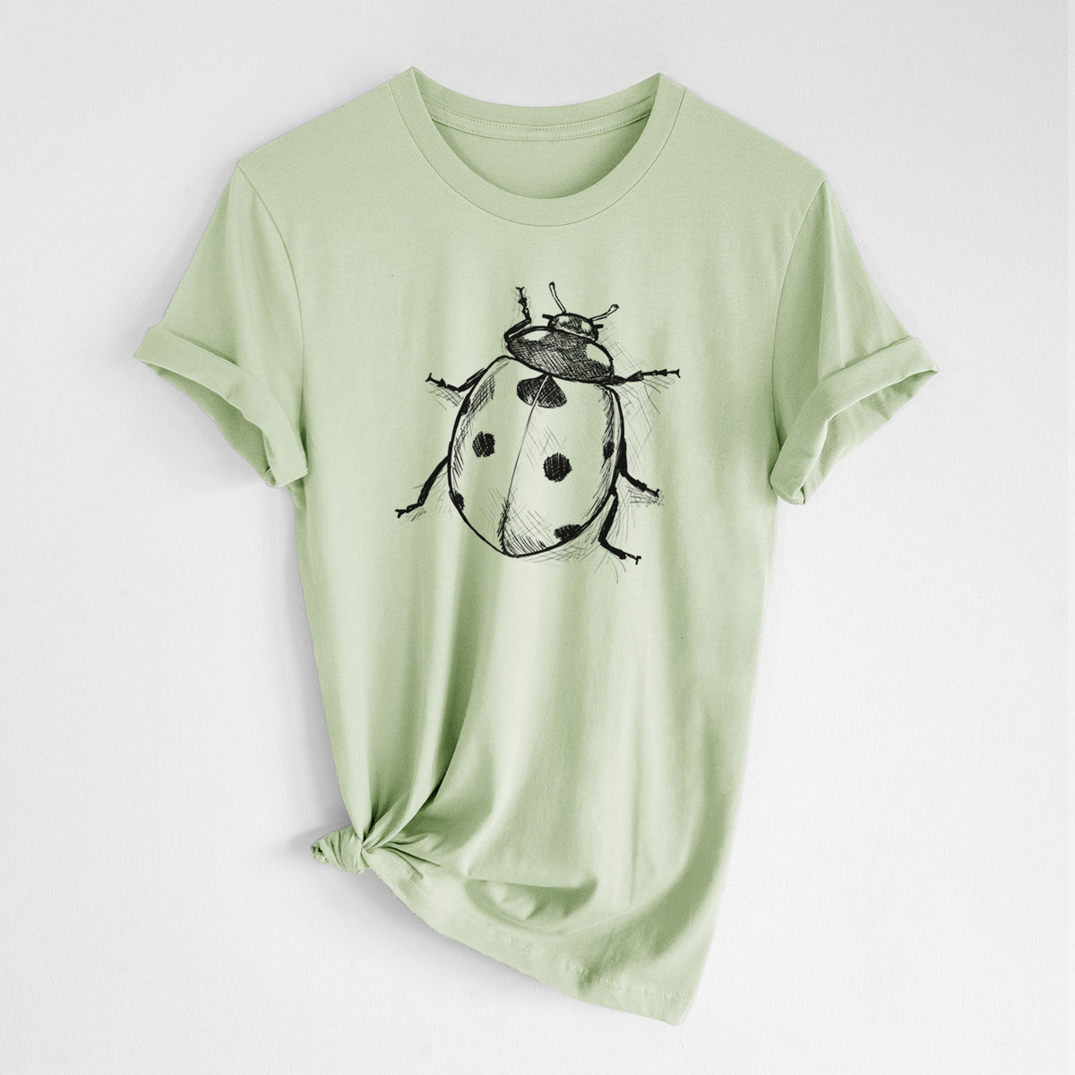 Spring green lightweight cotton t-shirt laid flat with the sleeves rolled, printed with a detailed black ink illustration of a seven-spot ladybird beetle.