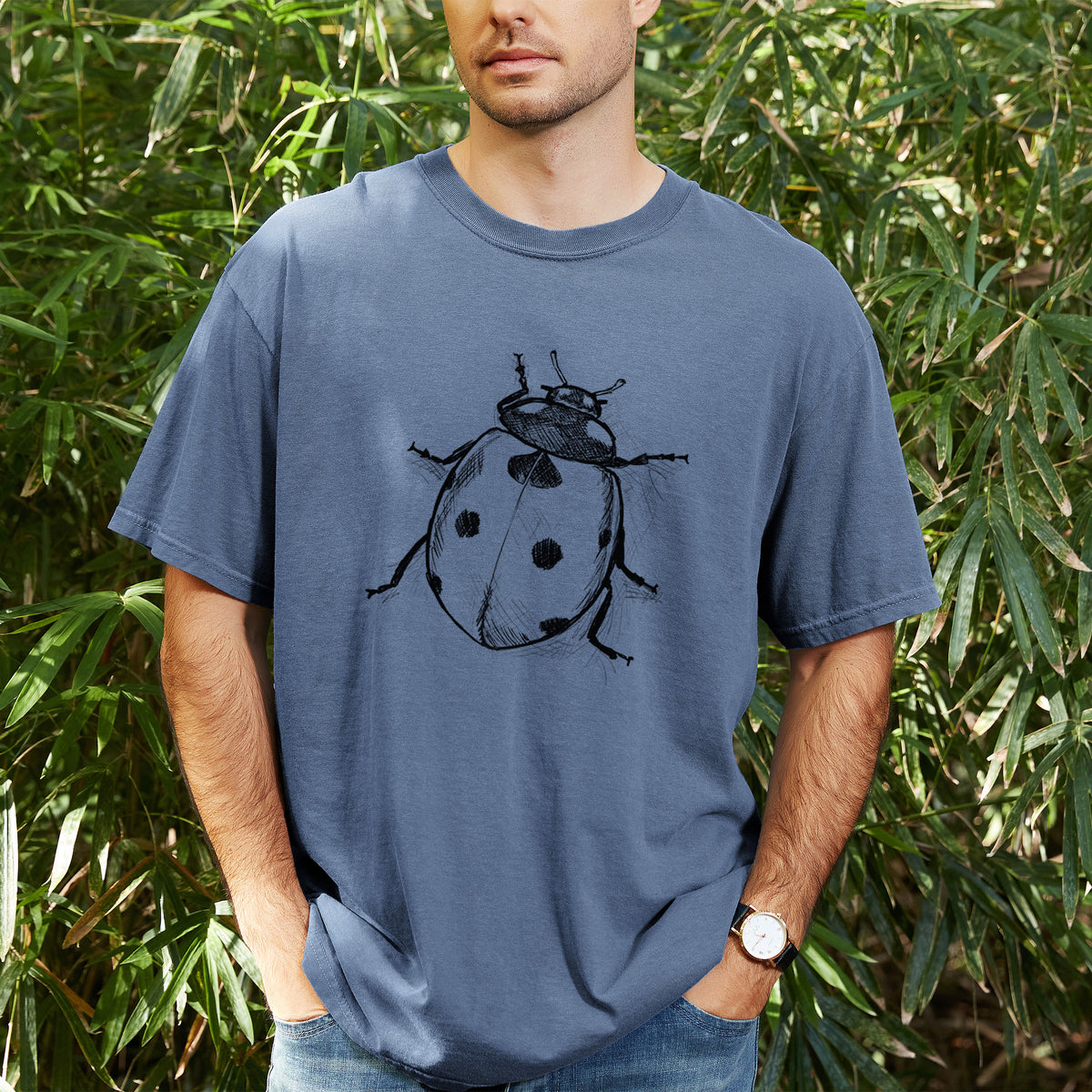 Man wearing a Comfort Colors t-shirt printed with a detailed black ink illustration of a seven-spot ladybird beetle, outdoors.