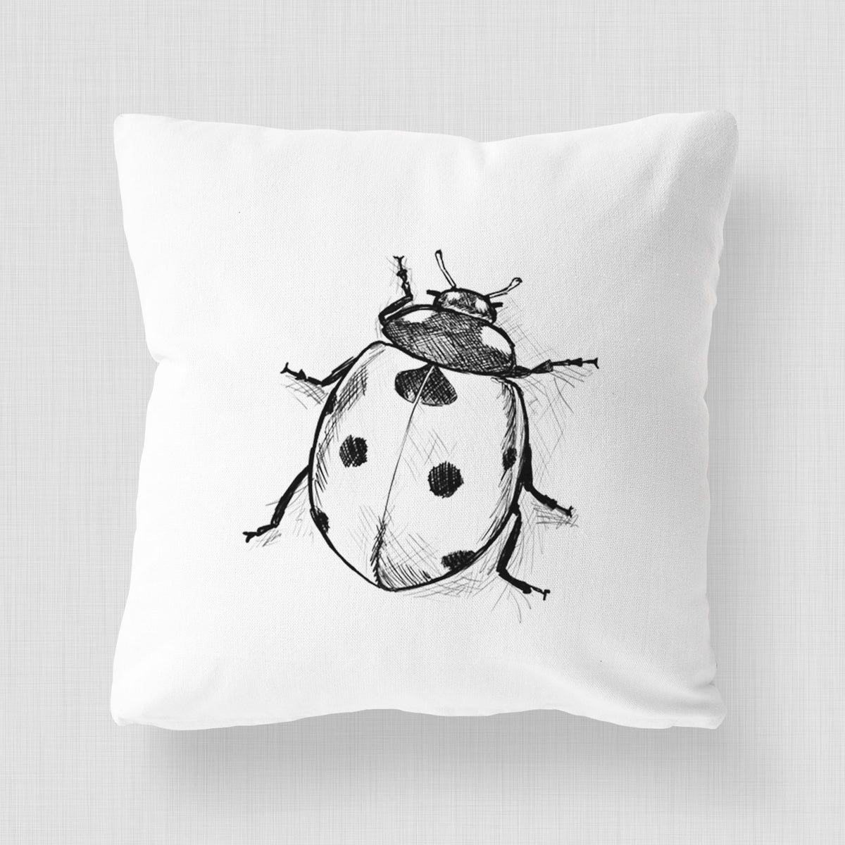 White pillow cover printed with a detailed black ink illustration of a seven-spot ladybird beetle.
