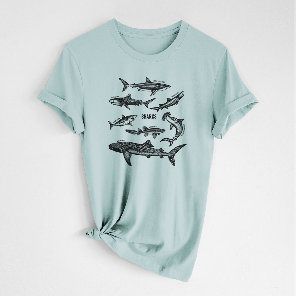 Dusty blue lightweight cotton t-shirt laid flat with the sleeves rolled, printed with a chart of black ink shark illustrations, including a whale shark, hammerhead and great white.
