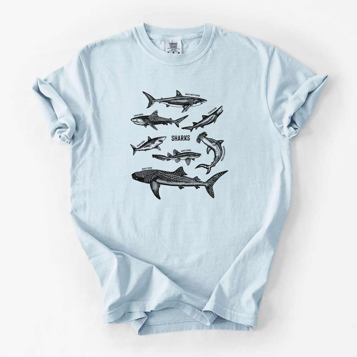 Chambray blue Comfort Colors t-shirt laid flat, printed with a chart of black ink shark illustrations, including a whale shark, hammerhead and great white.