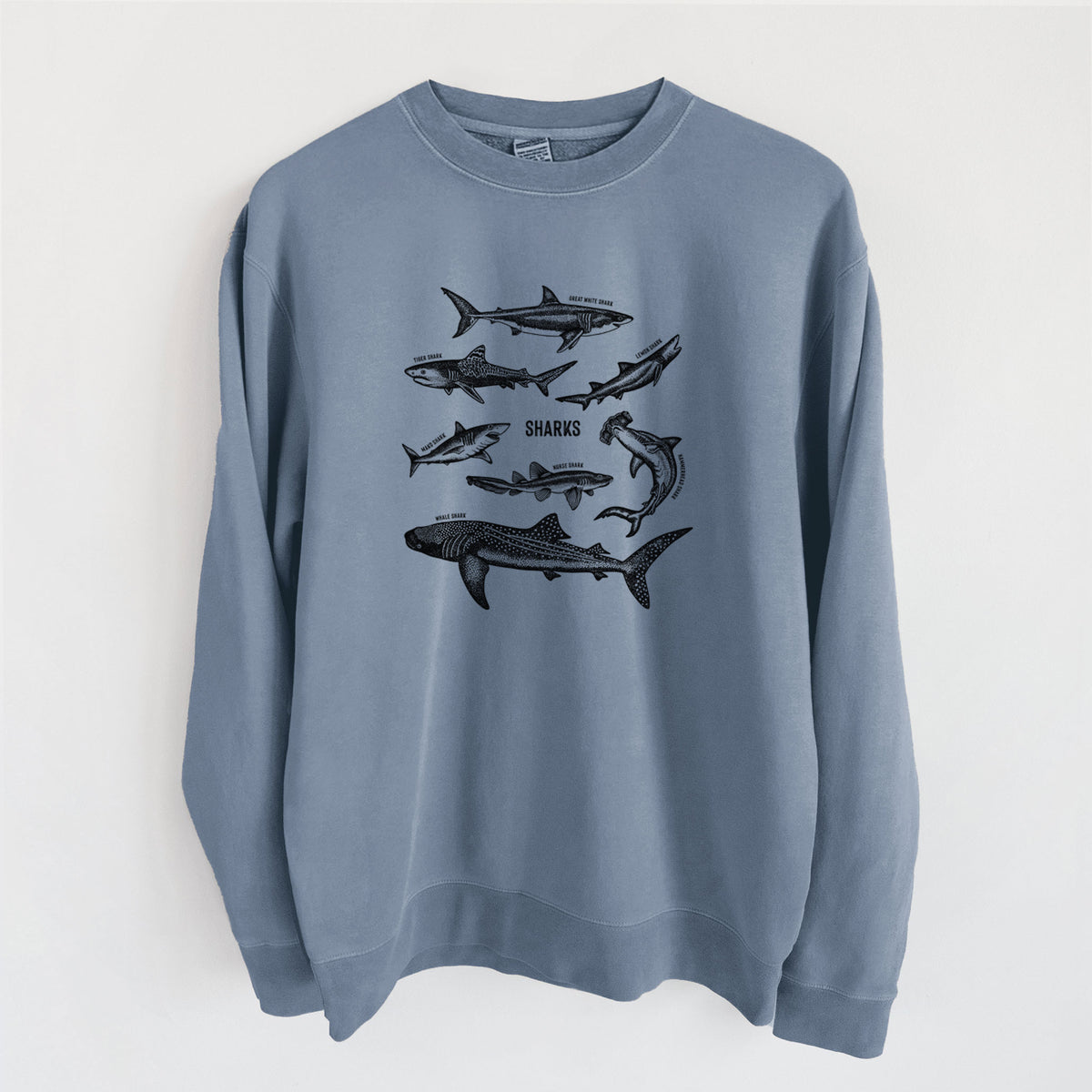 Slate blue pigment dyed crewneck sweatshirt laid flat, printed with a chart of black ink shark illustrations, including a whale shark, hammerhead and great white.
