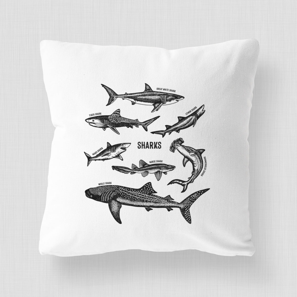 White pillow cover printed with a chart of black ink shark illustrations, including a whale shark, hammerhead and great white.
