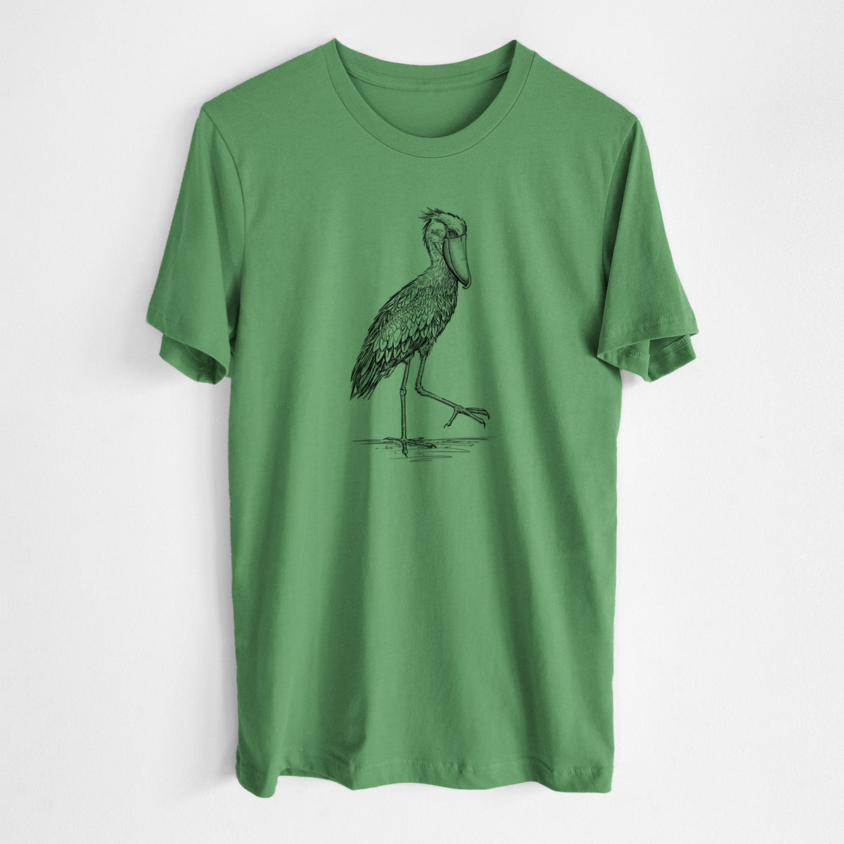 Leaf green lightweight cotton t-shirt laid flat, printed with a black ink illustration of a shoebill stork standing on one leg.