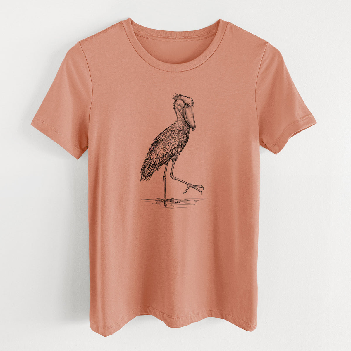 Terracotta orange women's relaxed fit cotton t-shirt laid flat, printed with a black ink illustration of a shoebill stork standing on one leg.