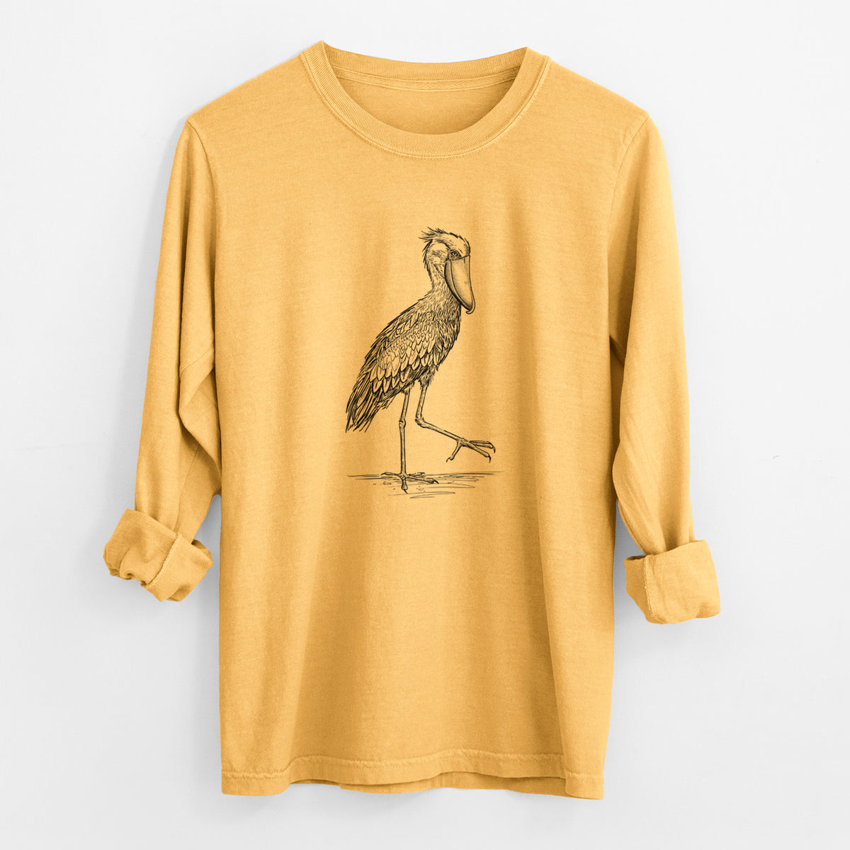 Golden wheat yellow Comfort Colors long sleeve shirt laid flat with the cuffs rolled, printed with a black ink illustration of a shoebill stork standing on one leg.