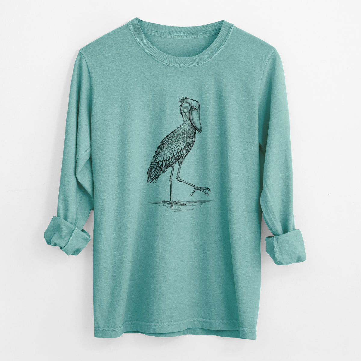 Reef green Comfort Colors long sleeve shirt laid flat with the cuffs rolled, printed with a black ink illustration of a shoebill stork standing on one leg.