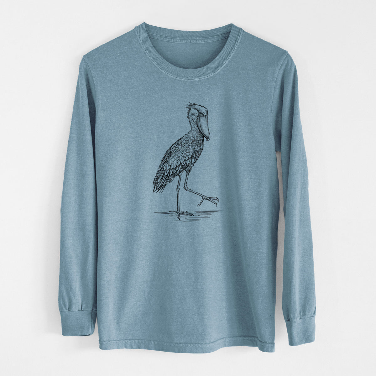 Steel blue Comfort Colors long sleeve shirt laid flat, printed with a black ink illustration of a shoebill stork standing on one leg.