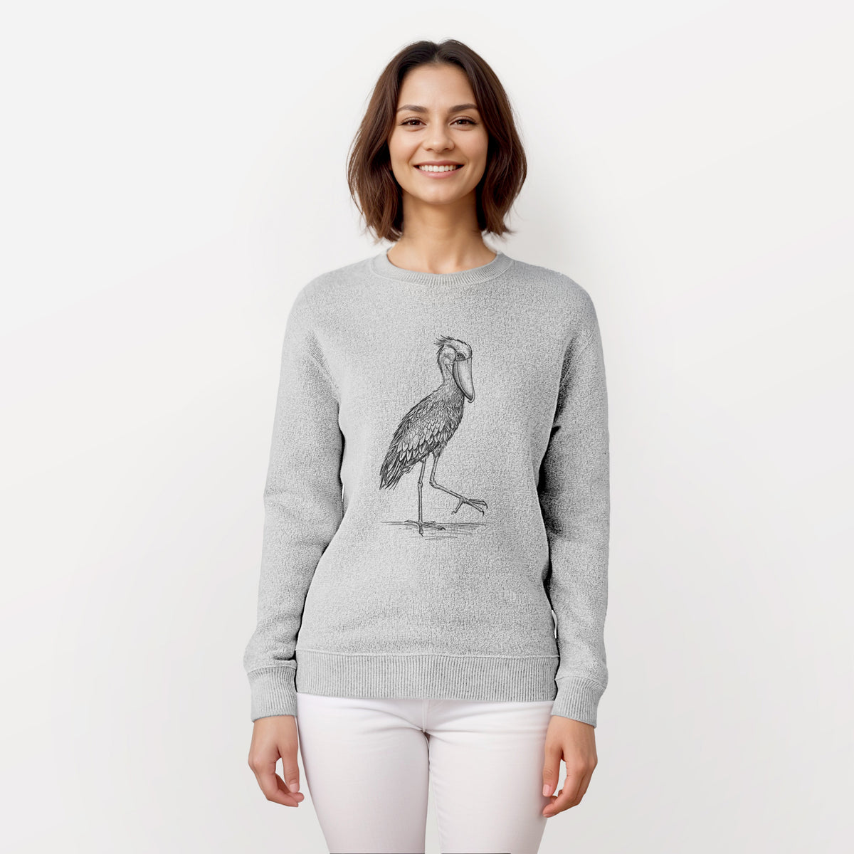 Woman wearing a knit sweatshirt printed with a black ink illustration of a shoebill stork standing on one leg.