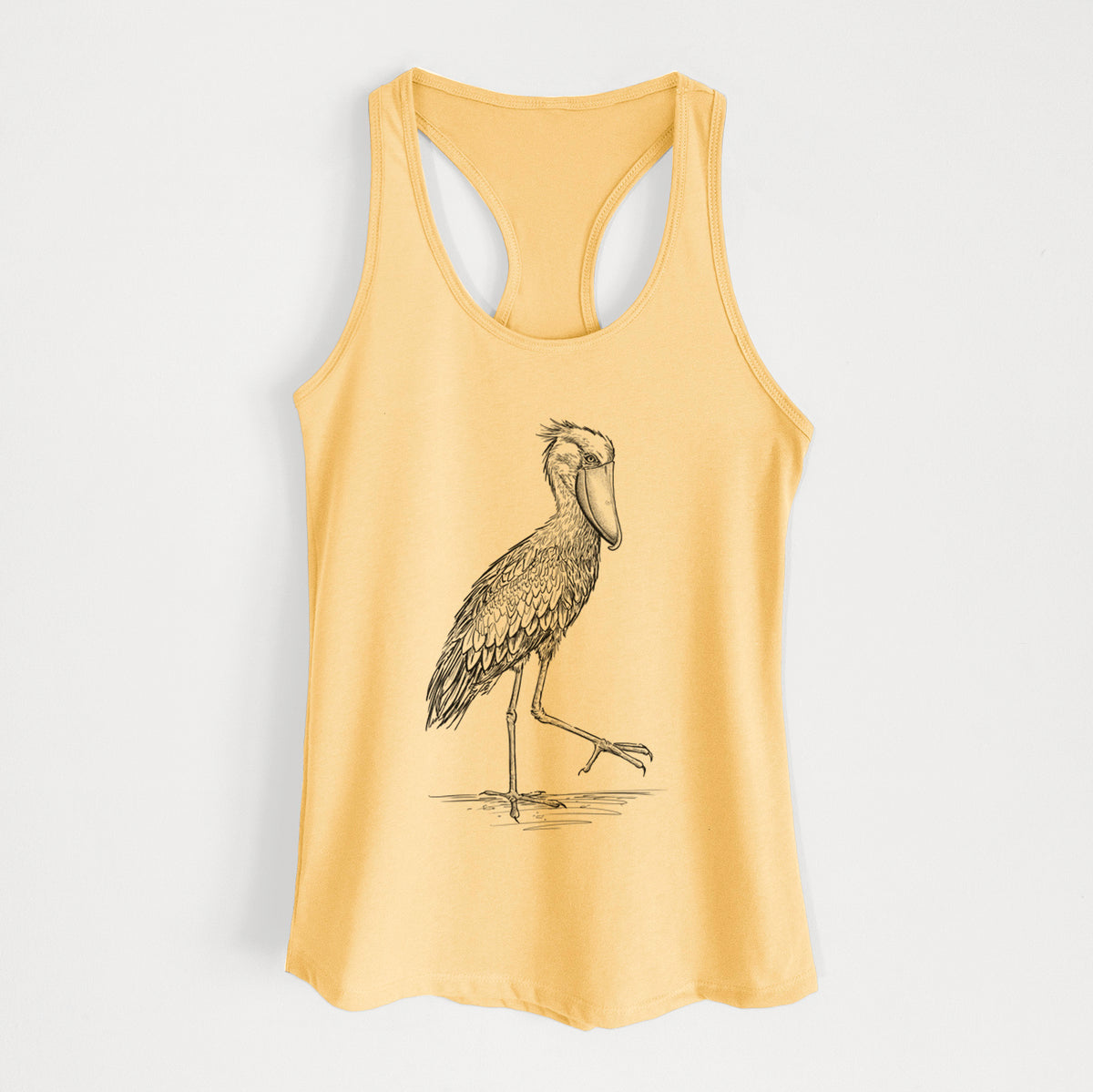 Banana cream women's racerback tank top laid flat, printed with a black ink illustration of a shoebill stork standing on one leg.