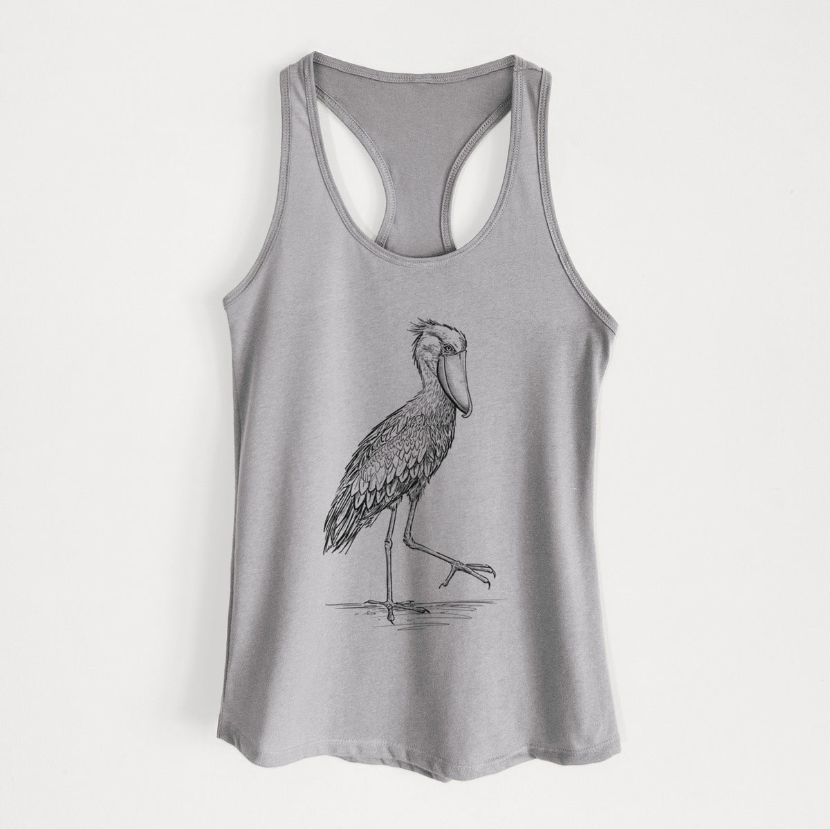 Heather grey women's racerback tank top laid flat, printed with a black ink illustration of a shoebill stork standing on one leg.
