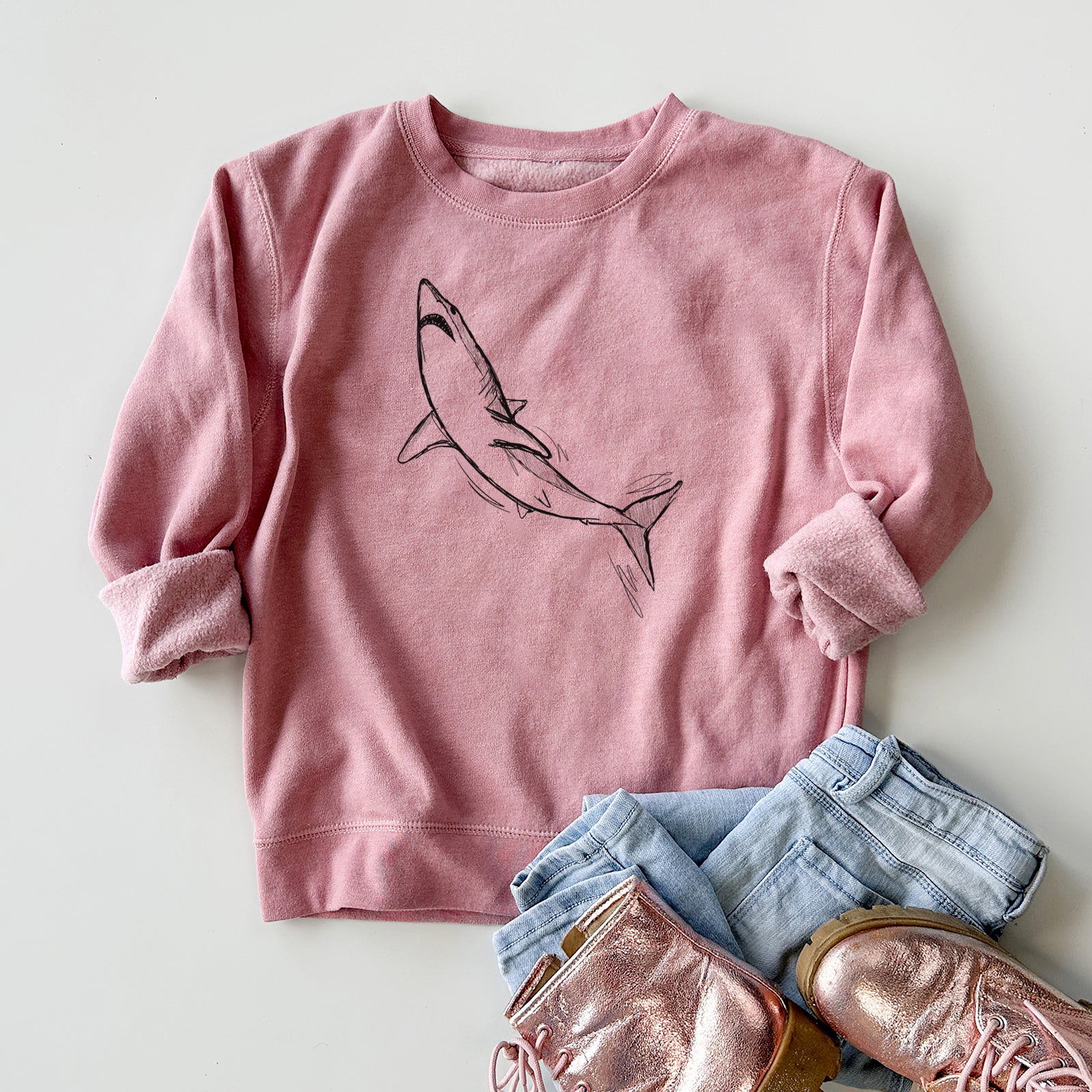 Boy wearing a youth crewneck sweatshirt printed with a black ink illustration of a shortfin mako shark diving, outdoors.