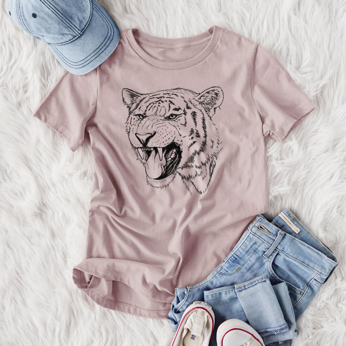 Women's relaxed fit cotton t-shirt printed with a detailed black ink portrait of a roaring Siberian tiger, styled flat on a white faux fur rug with jeans.