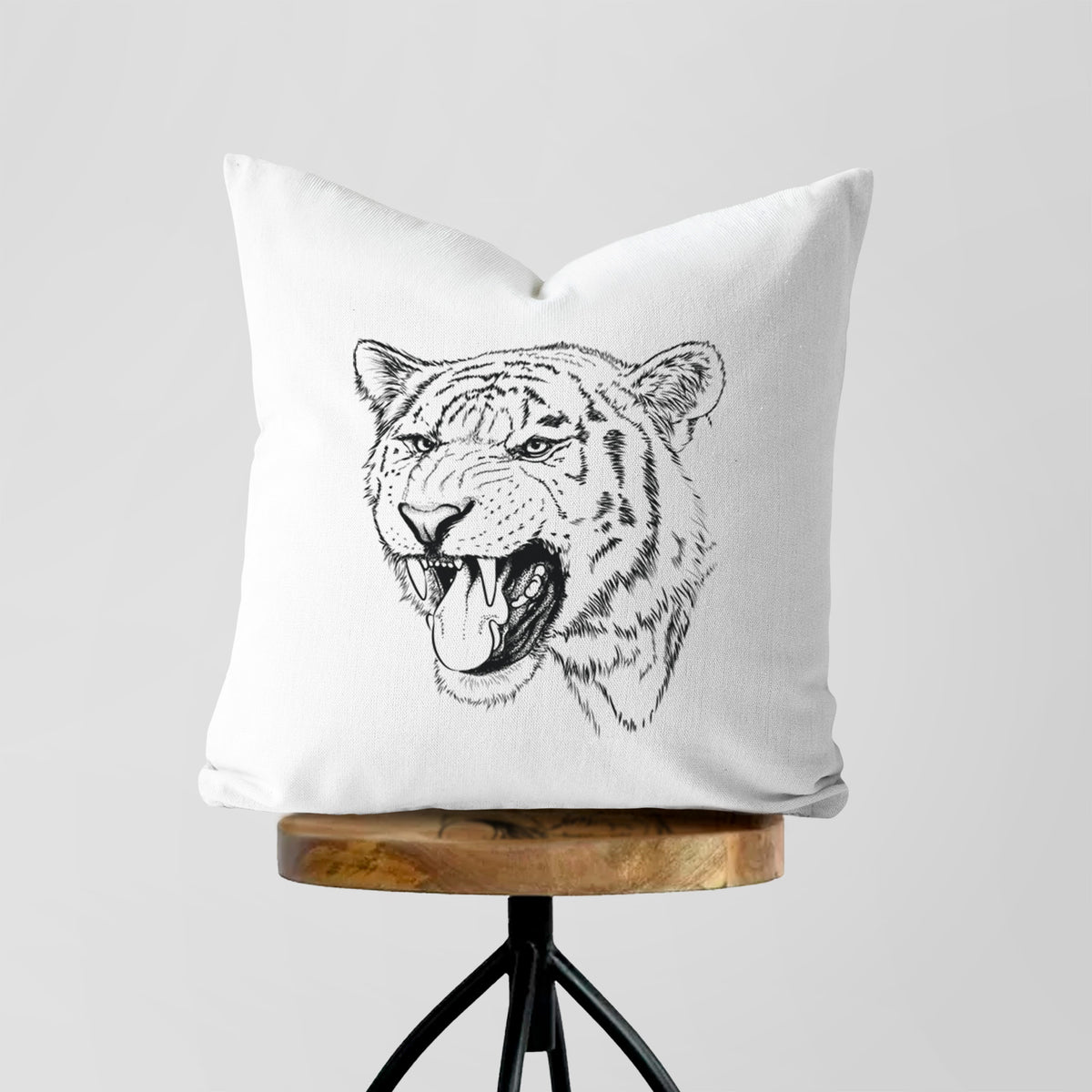White pillow cover printed with a detailed black ink portrait of a roaring Siberian tiger, on a wooden stool.