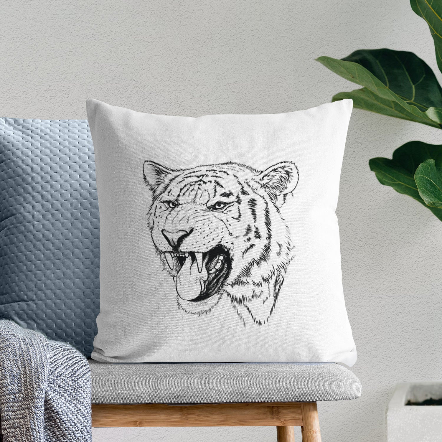 White pillow cover printed with a detailed black ink portrait of a roaring Siberian tiger, on a bench beside plants.